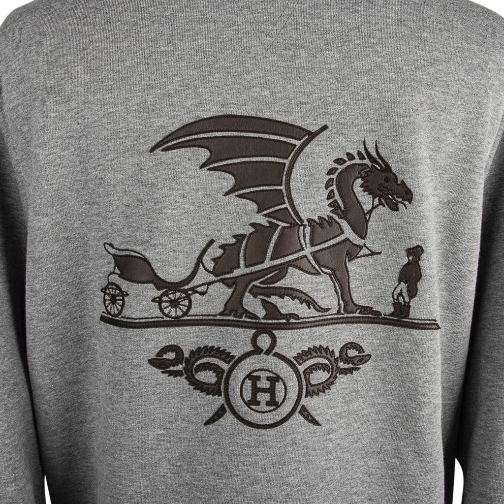 Guaranteed authentic Hermes Ex-Libris Dragon men's crewneck sweater in Gris.
Depicts the iconic Hermes carriage and footman with a dragon beautifully crafted in black lambskin with an embellished 