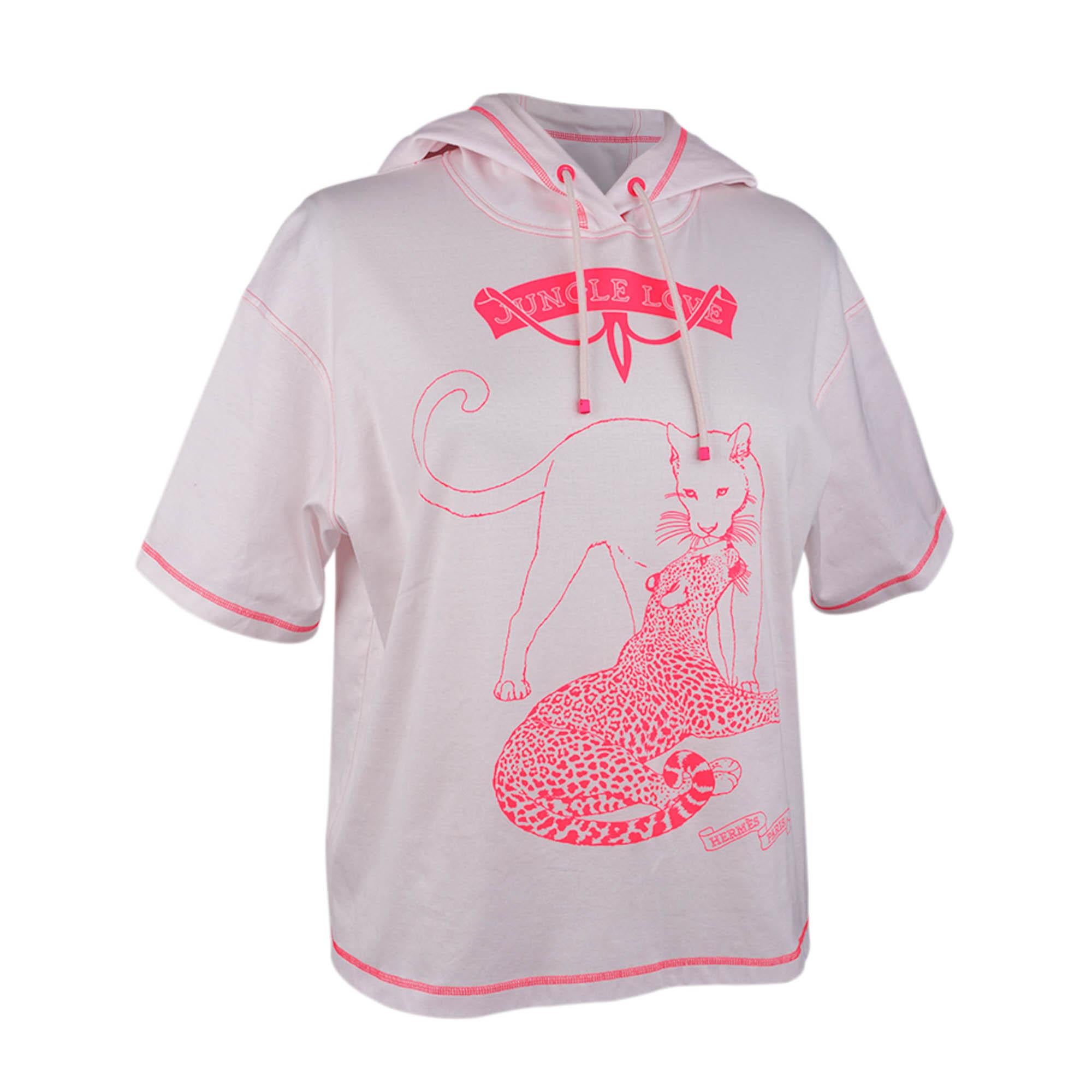 T-shirt à capuche Hermès Jungle Love en rose porcelaine avec des touches de rose vif.
Ce haut à imprimé Jungling Love bien-aimé est exécuté en contraste et présente une coupe boxy avec des manches courtes.
La capuche est munie d'un cordon tressé.
Le