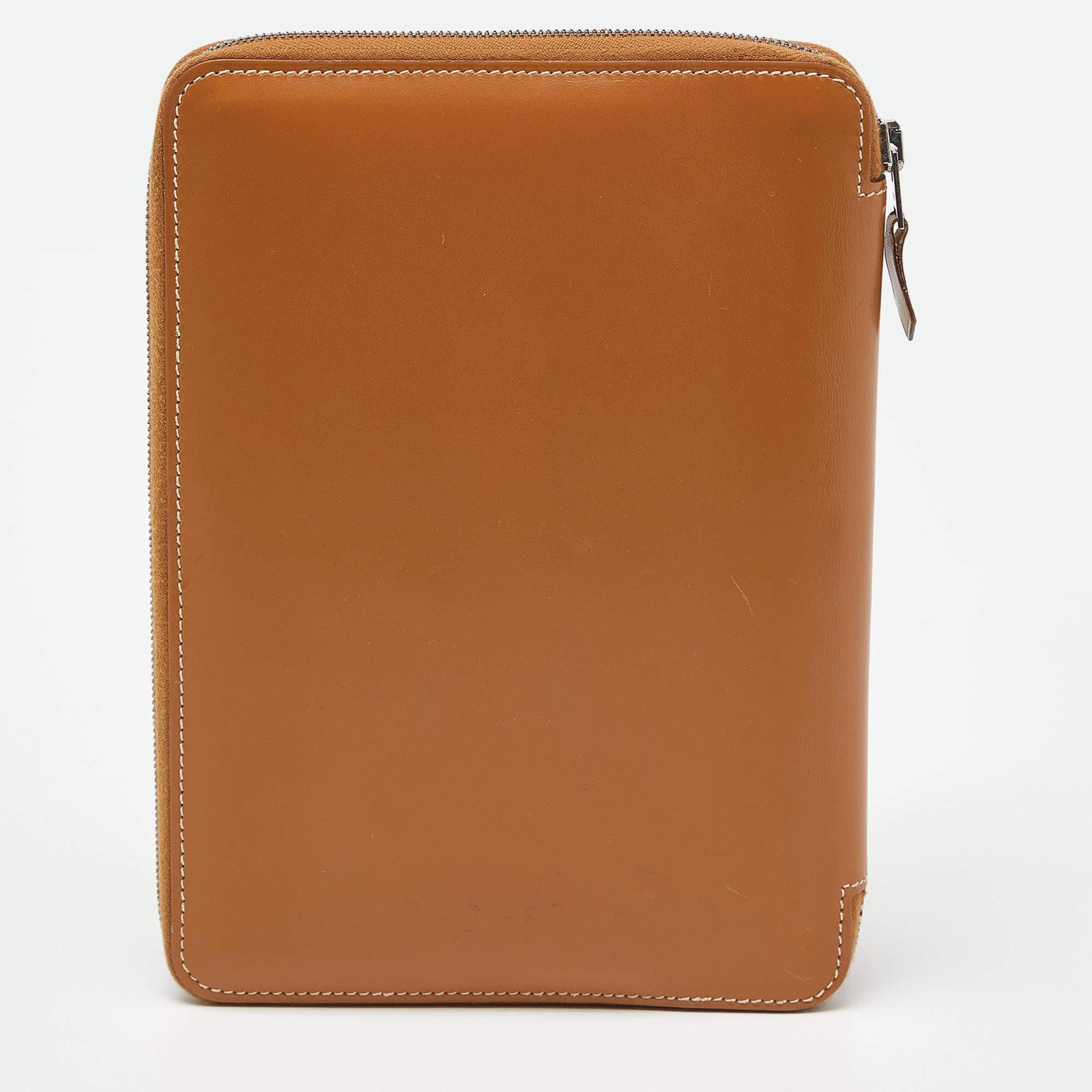 Write a lot and keep your words tucked away safely with this globe trotter agenda from the house of Hermés. Crafted from Tabac Camel Swift leather, it has contrast stitching and a zip closure with a notebook inside. It's the perfect companion for