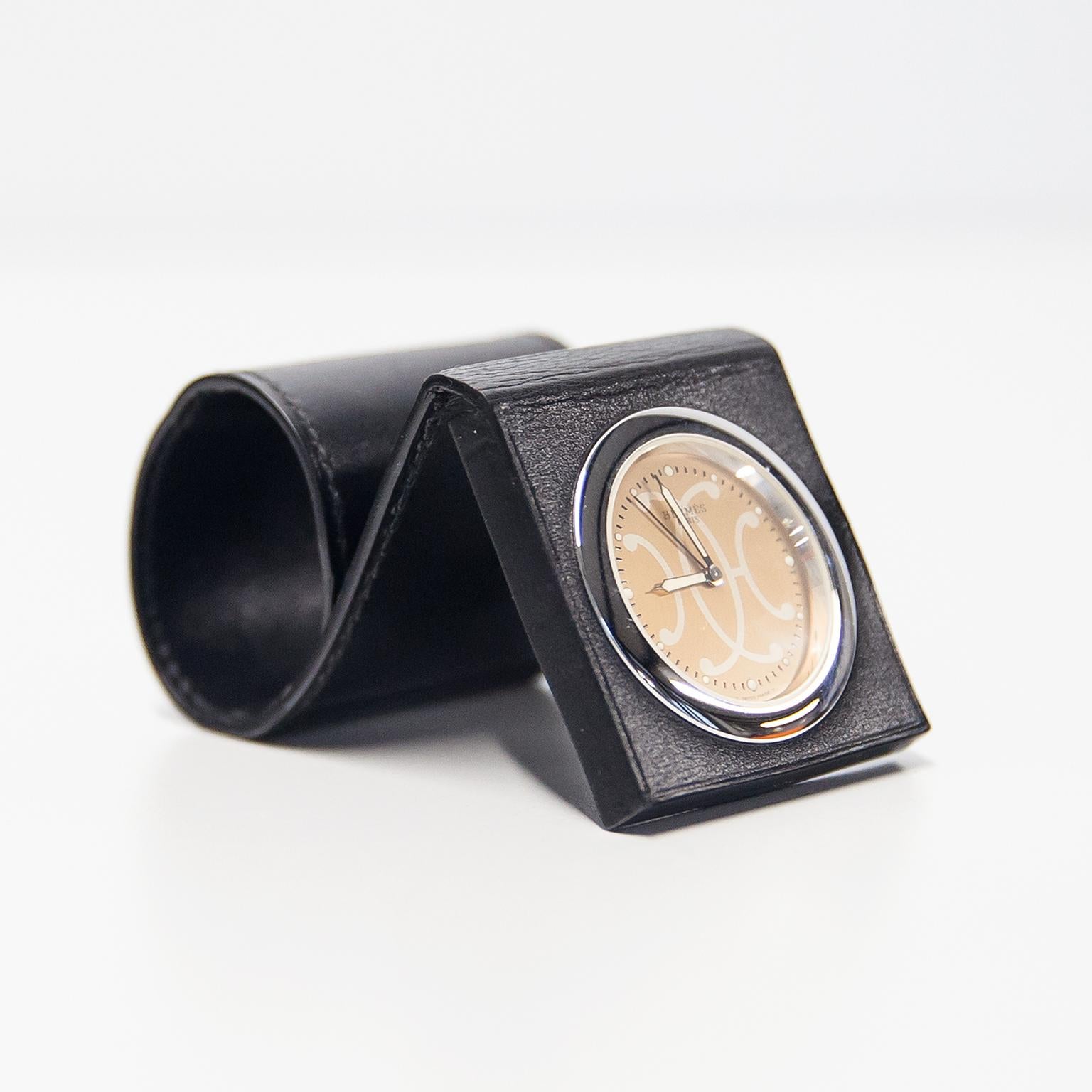 Very elegant Hermès travel alarm clock model QU 1.703 in steel and black leather with protective leather folding case with gold dial. Includes the beautiful box in leather and fine fabric. The clock has a battery-operated quartz movement and is in