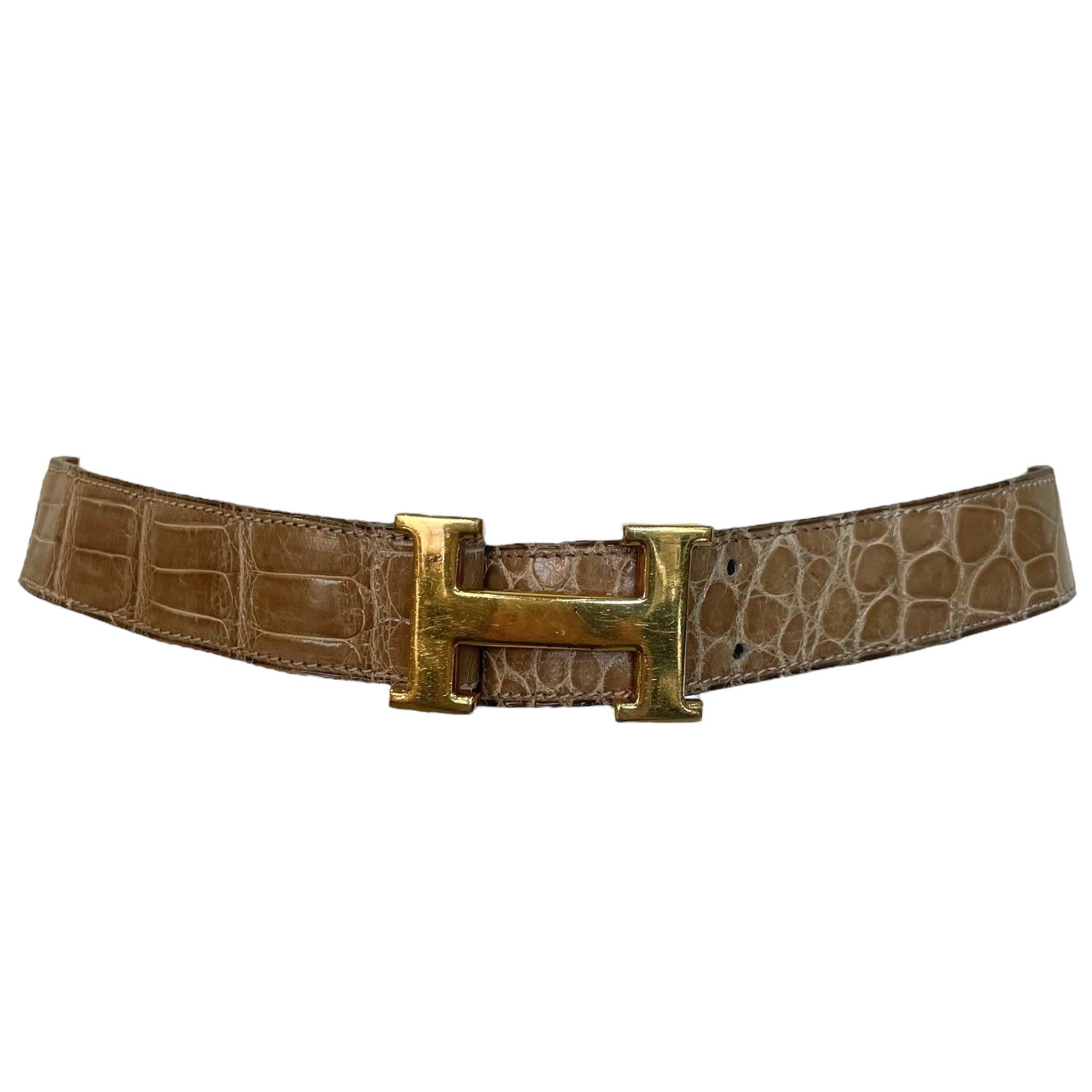 Classica fibbia da cintura Constance con logo 'H' in metallo placcato oro giallo da 38 mm. Cinturino in pelle di alligatore Mississippiensis lucido e marrone. La fibbia Constance presenta leggeri graffi superficiali. La cintura può essere regolata