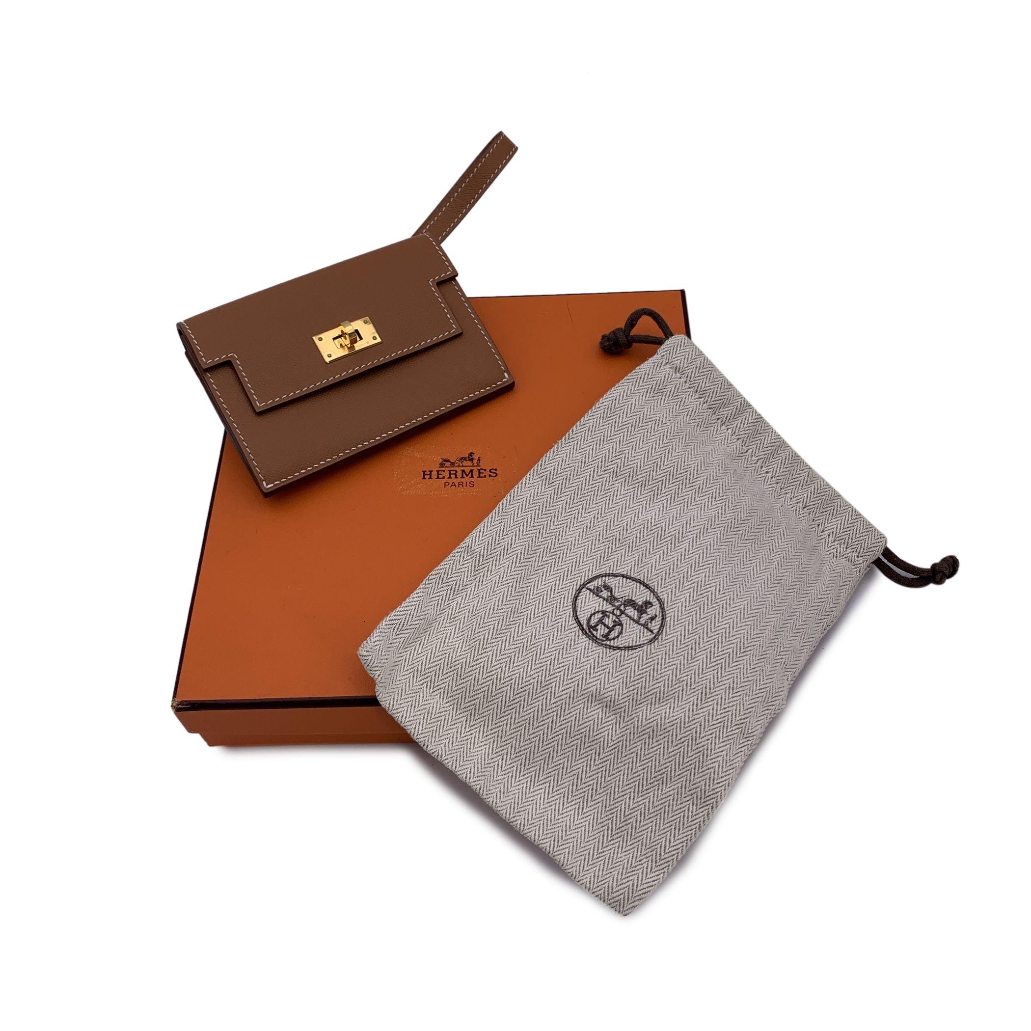 Hermes Kelly Slim Wallet in tan beige Epsom leather with gold metal hardware. It features flap with turnlock closure and a removable wristlet strap. Tan leather internior. 1 open compartment, 1 zip compartment and 1 flat pocket inside. 'Hermes