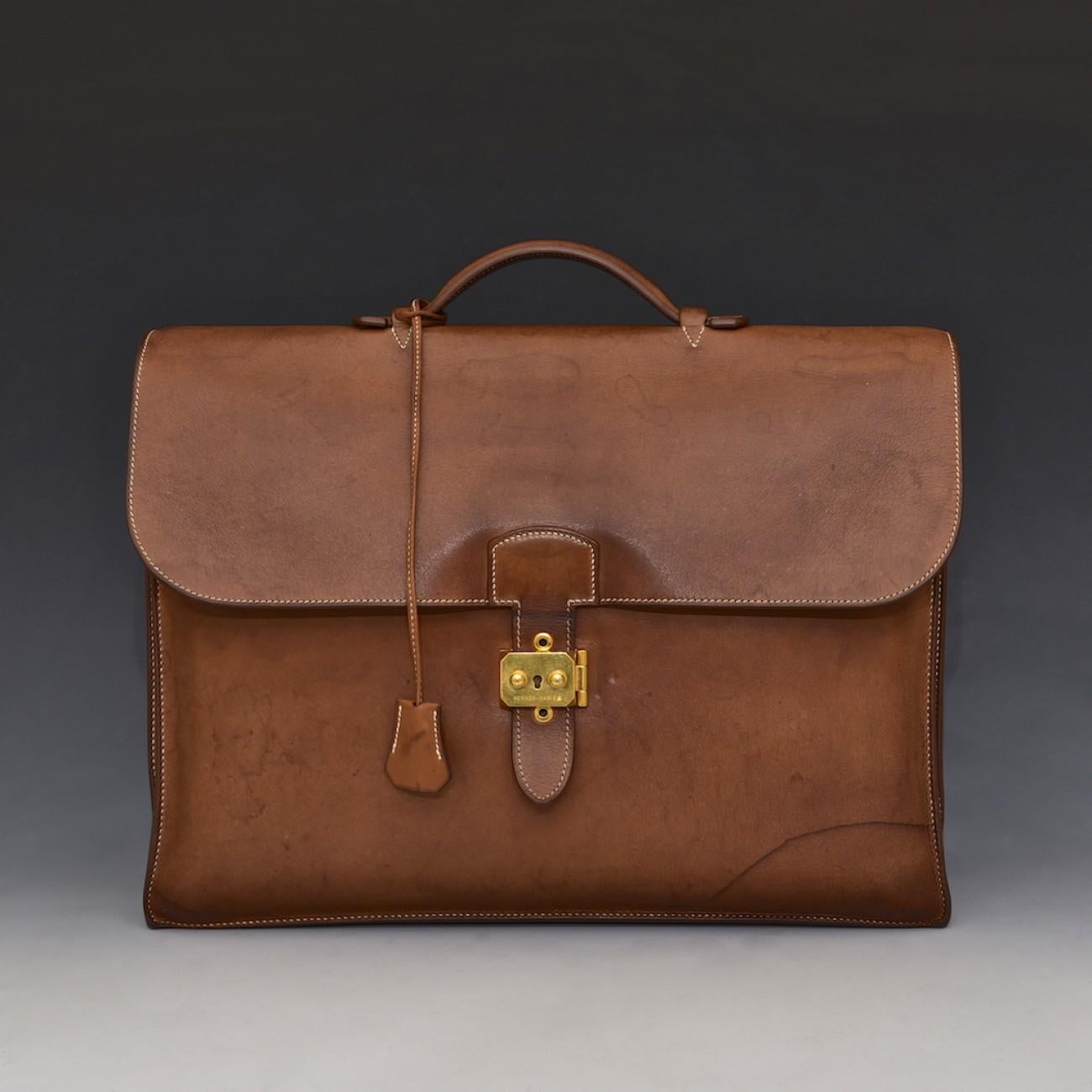 A stylish tan leather three pocket 'Sac à Dépêches' by Hermès; a design that can trace its origins back to 1928. One of the best looking briefcases we've seen; this case has a gold plated lock, comes complete with clochette and a key, is not