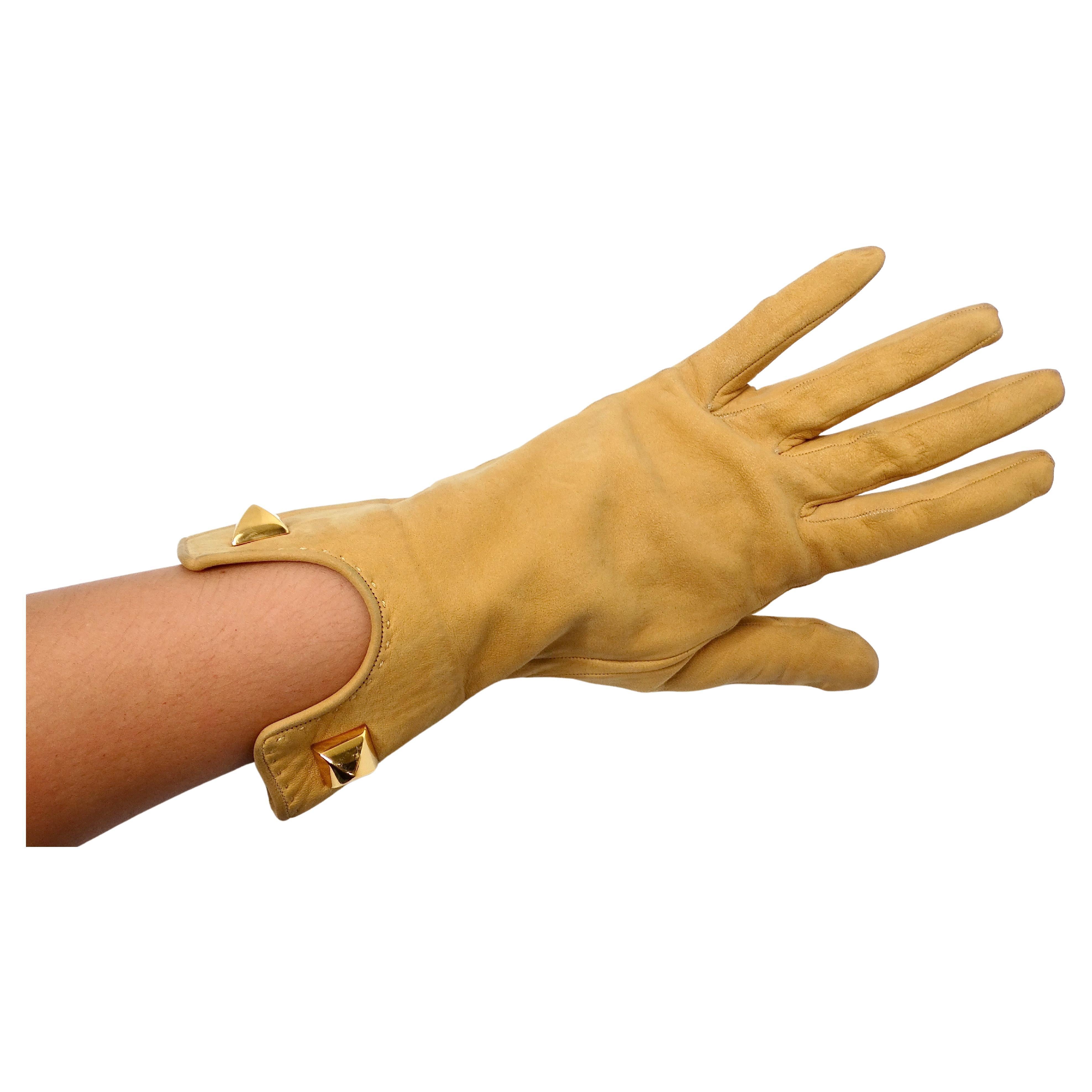 The Hermes Tan Suede Leather Rockstud Gloves from the circa 1990s epitomize luxury craftsmanship and timeless elegance. Crafted from supple tan suede leather, these gloves exude a soft, velvety texture that enhances their sophisticated appeal. The