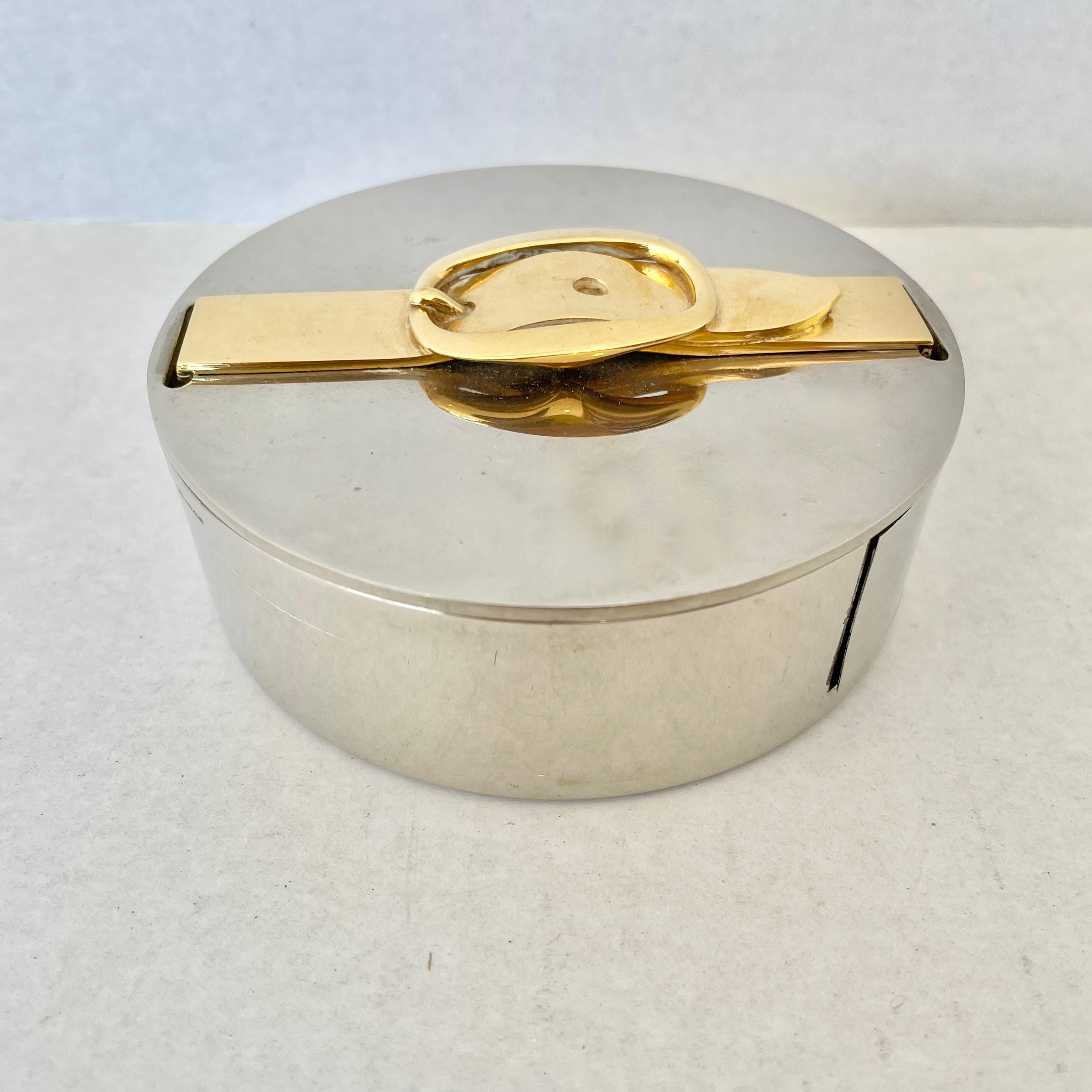 Classic vintage Hermès tape dispenser in silver with a brass belt buckle detail. Hermès PARIS, Made In France stamped on outer rim. Dispenser has a lid which opens up in order to easily switch rolls of tape out. Beautiful and functional accent piece