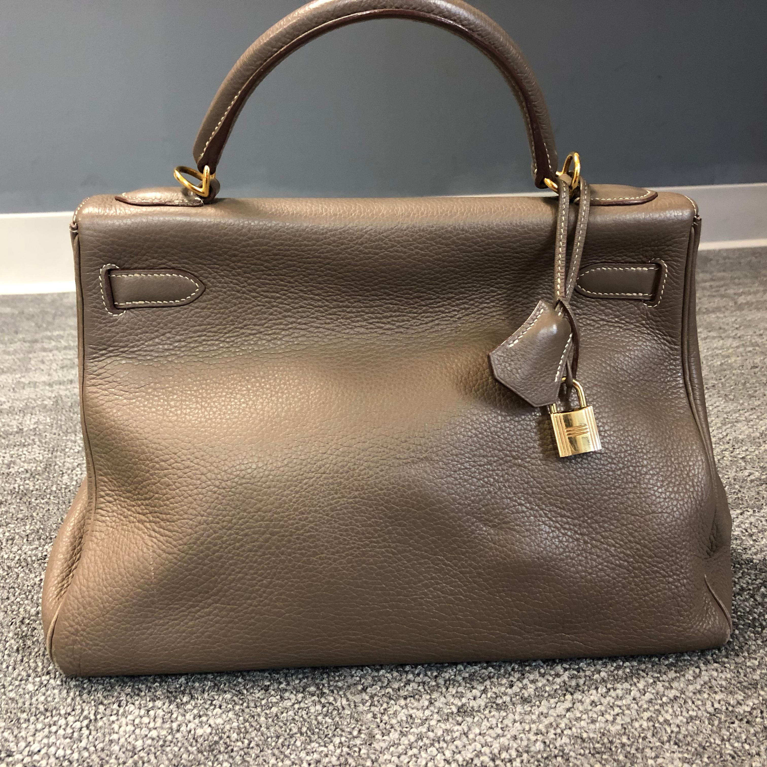 Il s'agit du sac Hermès Kelly Sellier 32 fabriqué en cuir d'Epsom.

A l'intérieur, il y a trois poches plates, l'une d'entre elles possède une fermeture éclair Hermès avec une patte en cuir. La languette doit être en ligne droite avec la fermeture