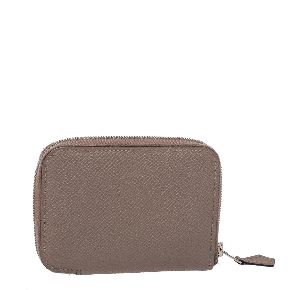An ideal creation, this Hermes wallet is a must-have! It has been styled in a zip-around silhouette using durable, grey-hued leather. The insides are leather-lined and equipped with card slots and open compartments to arrange your cash or