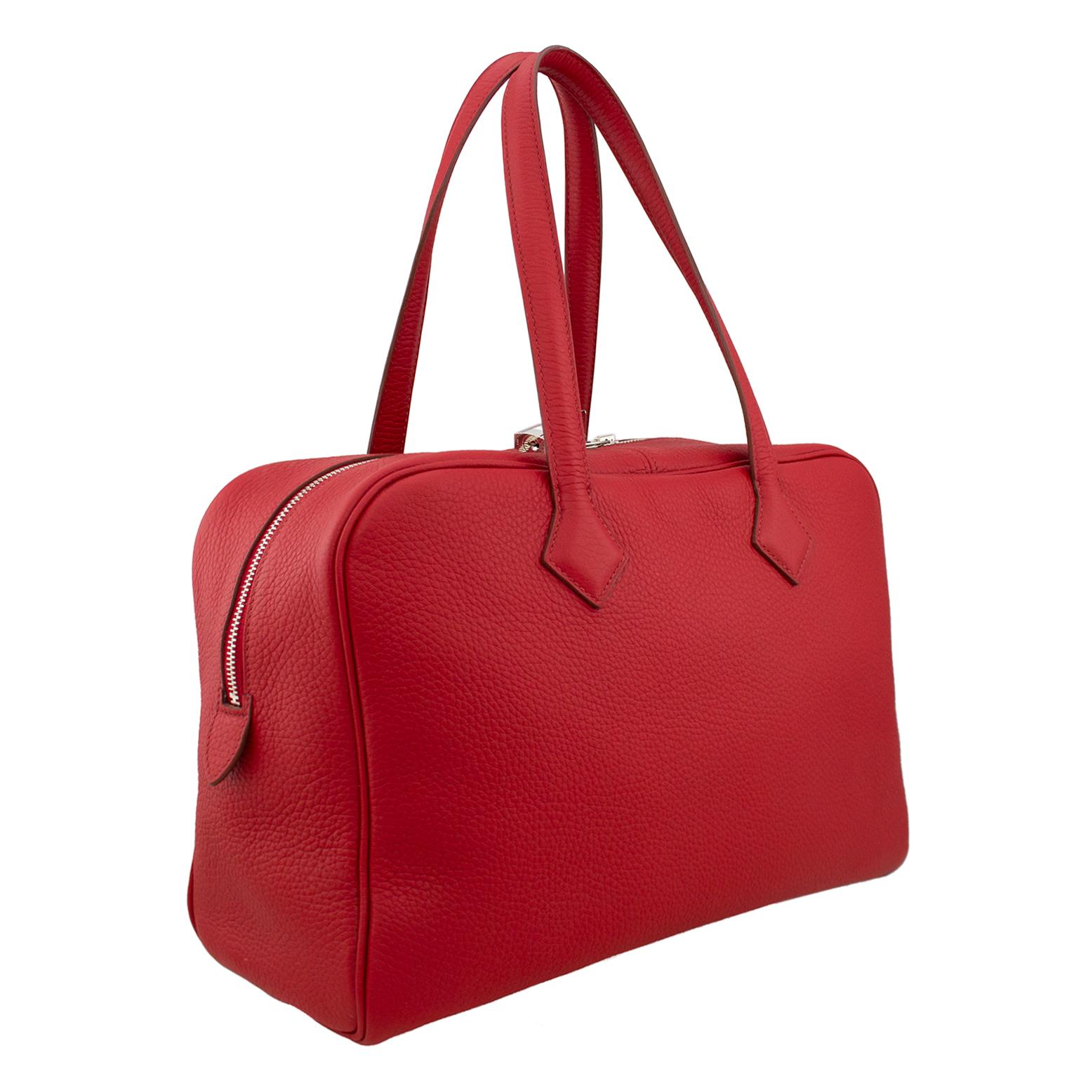Authentic Hermes Taurillon Novillo Victoria II 35 in rouge garance. This stylish tote is crafted of fine Taurillon Novillo leather in red. It features very tall leather strap handles, a double palladium zipper with lock and opens to a beige