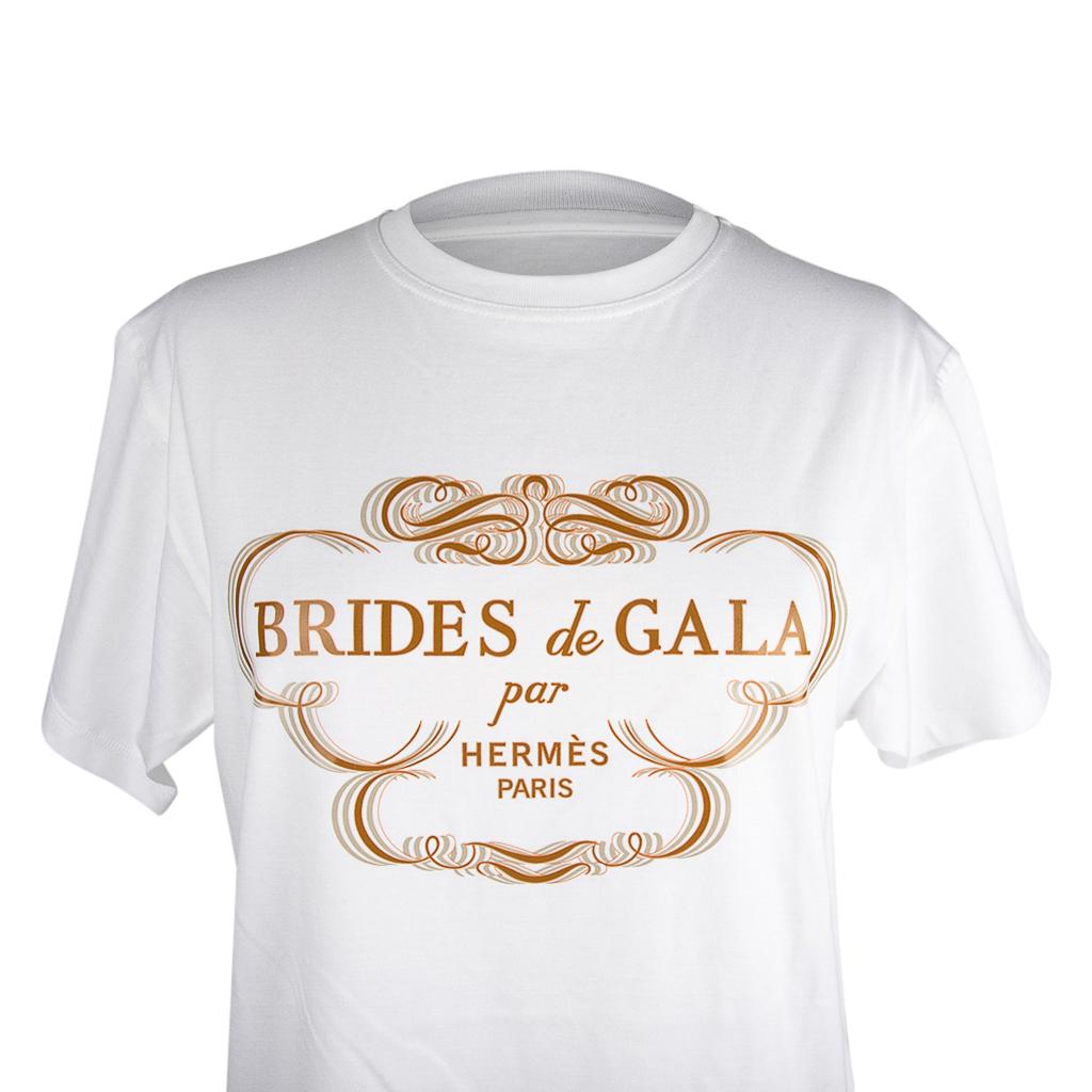 Mightychic offers an Hermes Brides de Gala Tee Shirt.
The iconic Brides de Gala motif expressed in Gold writing on White.
Crew neck and short sleeves.
Fabric is cotton jersey.
NEW or NEVER WORN.
final sale

SIZE  38
USA SIZE 6

TOP MEASURES:
LENGTH 