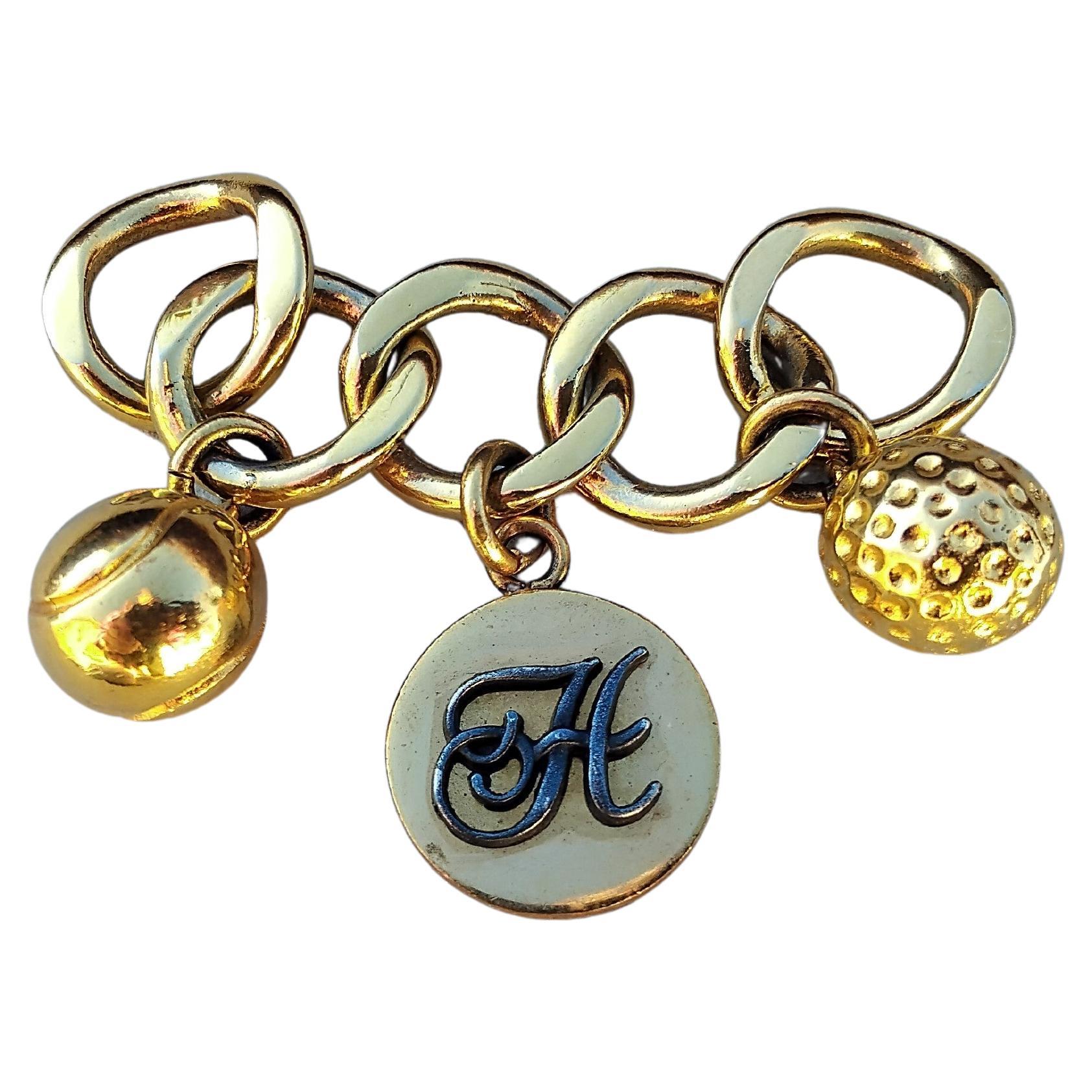 Lovely Authentic Hermès Charm

5-link chain holding 3 tassels: 1 tennis ball, 1 medal decorated with an H, 1 golf ball

Please note: this charm adorned Hermès gloves. It is not signed Hermès, just the H on the middle medal. It has NO closing