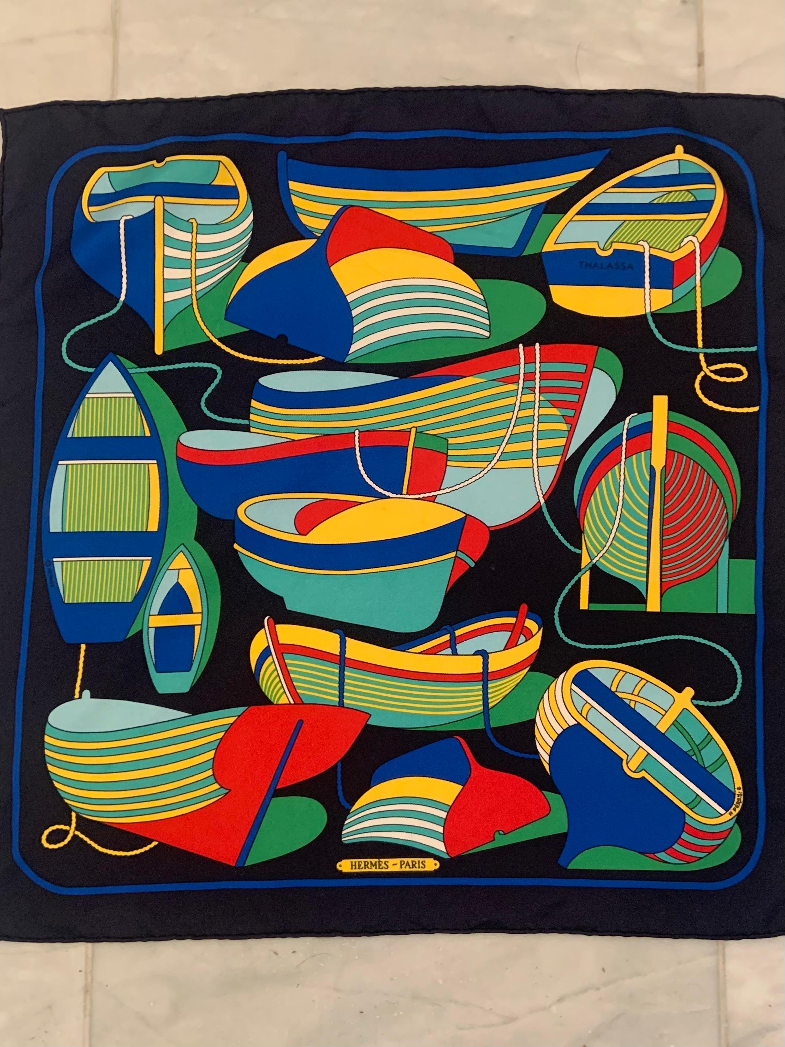This Hermes Thalassa pattern small silk scarf, neckerchief or pocket square is so evocative of summer on a Greek Island. The colorful fishing boats set against the navy blue background fill the space between the bright blue border, and the mooring
