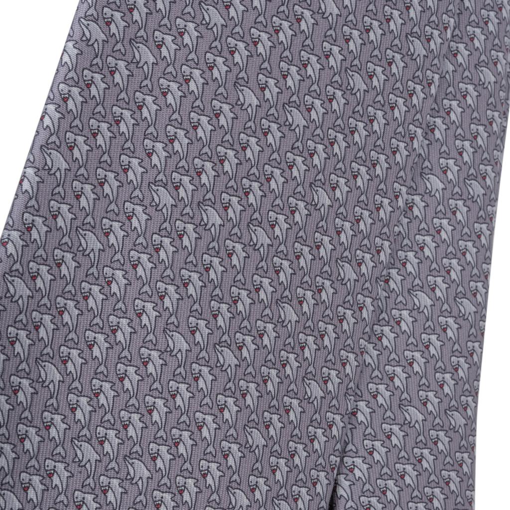 Guaranteed authentic Hermes Cache-Cache Aquatique mens silk tie.
Charming and whimsical shark motif a perfect addition to any wardrobe.
Rear interior has swimming sharks!
Gris, Gris Clair and Acier colour way.
Tie width is 8 cm.
NEW or NEVER