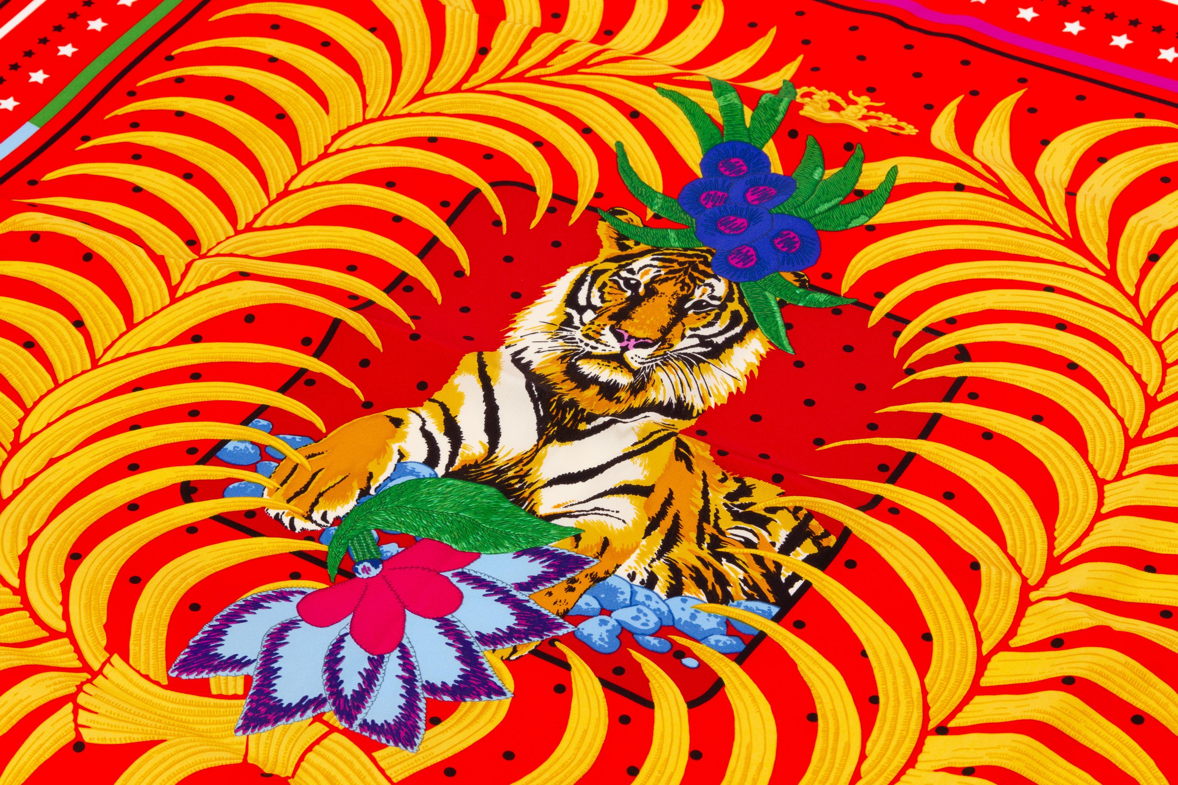 New Hermès Tigre Royal Fleuri Scarf. The piece is made out of 100 percent silk and comes with the original box. The print shows a royal tiger who is crowned by some flowers over his head.