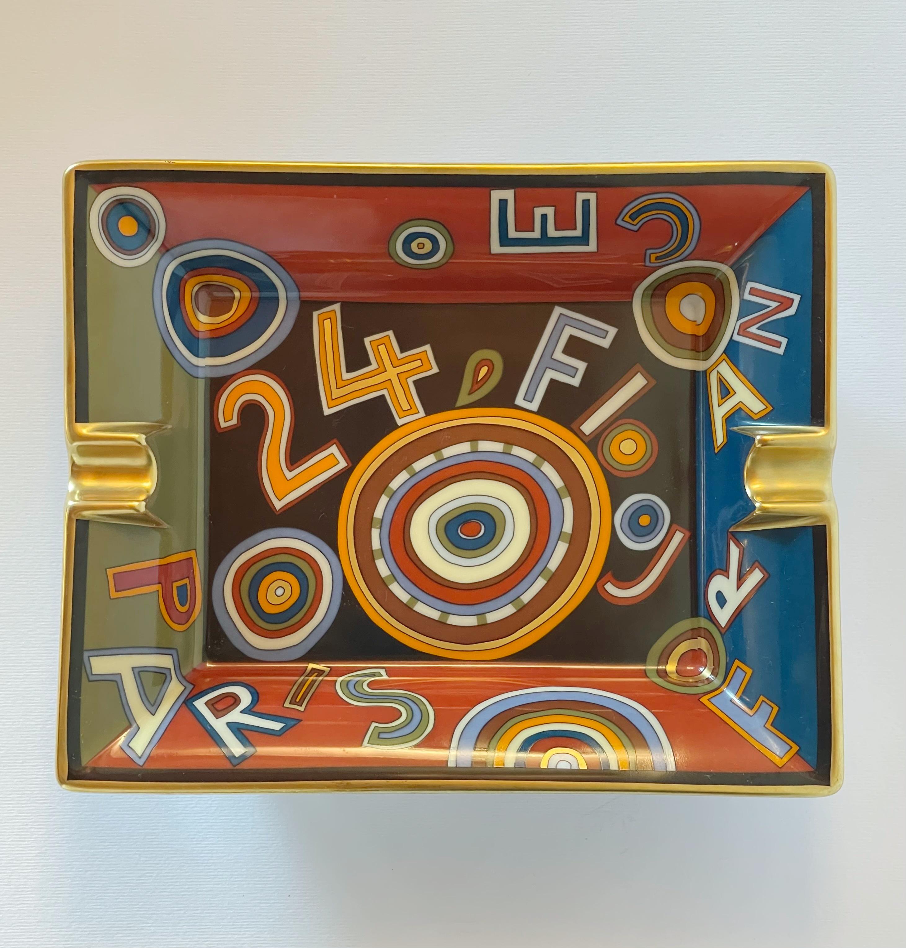 Limited Edition Hermes Tohu Bohu mehrfarbige Porzellan-Videopoche, Kleingeldschale, Taschenentleerer oder Aschenbecher, mit Einkerbungen und vergoldetem Rand und mit Leder bezogenem Boden / Made in France
Auf dem Anhänger steht 