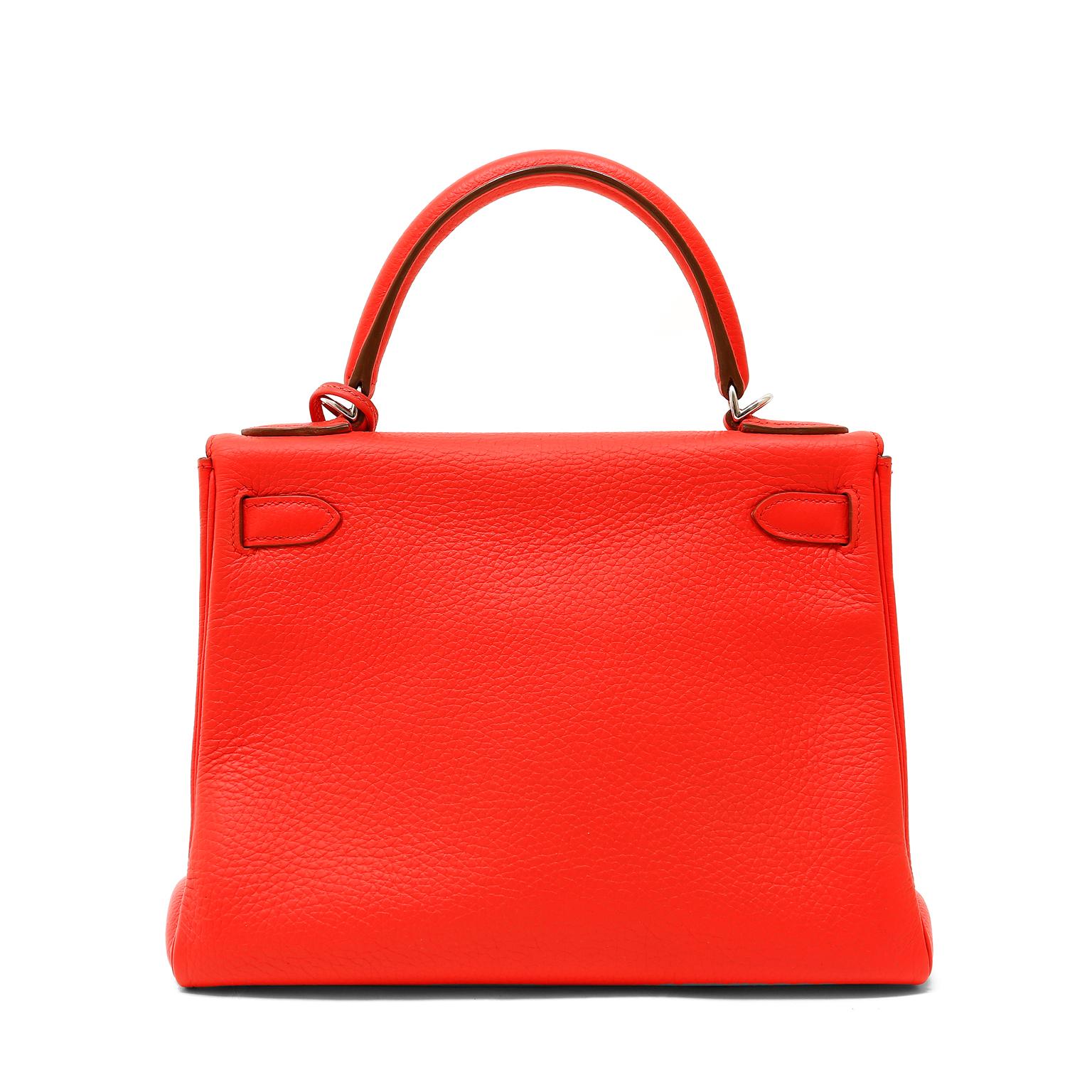 This authentic Hermès Tomato Red Togo Leather 28 cm Kelly is in excellent condition.  The ladylike Kelly is in high demand and requires extensive waiting periods from Hermès.  Vibrant bright red paired with Palladium hardware is a brilliant pop of