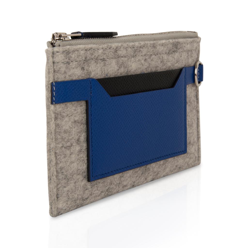 Guaranteed authentic Hermes Toodoo Mini Colorblock change purse features wool felt and leather.
Grey felt with Epsom leather Blue Electric slots on each side. 
Front is accented with black epsom.
D ring on side.
New or Store Fresh Condition.
Comes