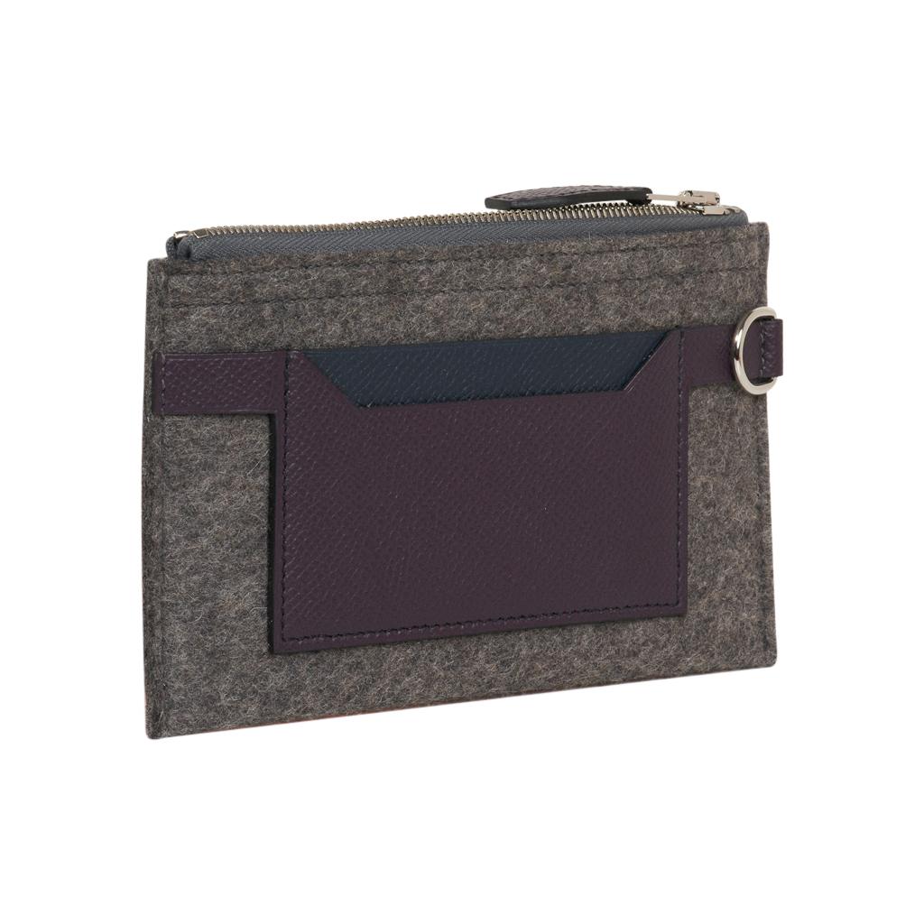 Hermes Toodoo Mini Colorblock change purse.
Has zip closure and 2 external credit card slot pockets, and D ring.
Featured in Grey wool felt with Plum and Black leather.
D ring on side.
New or Store Fresh Condition.
Comes with signature Hermes box.
