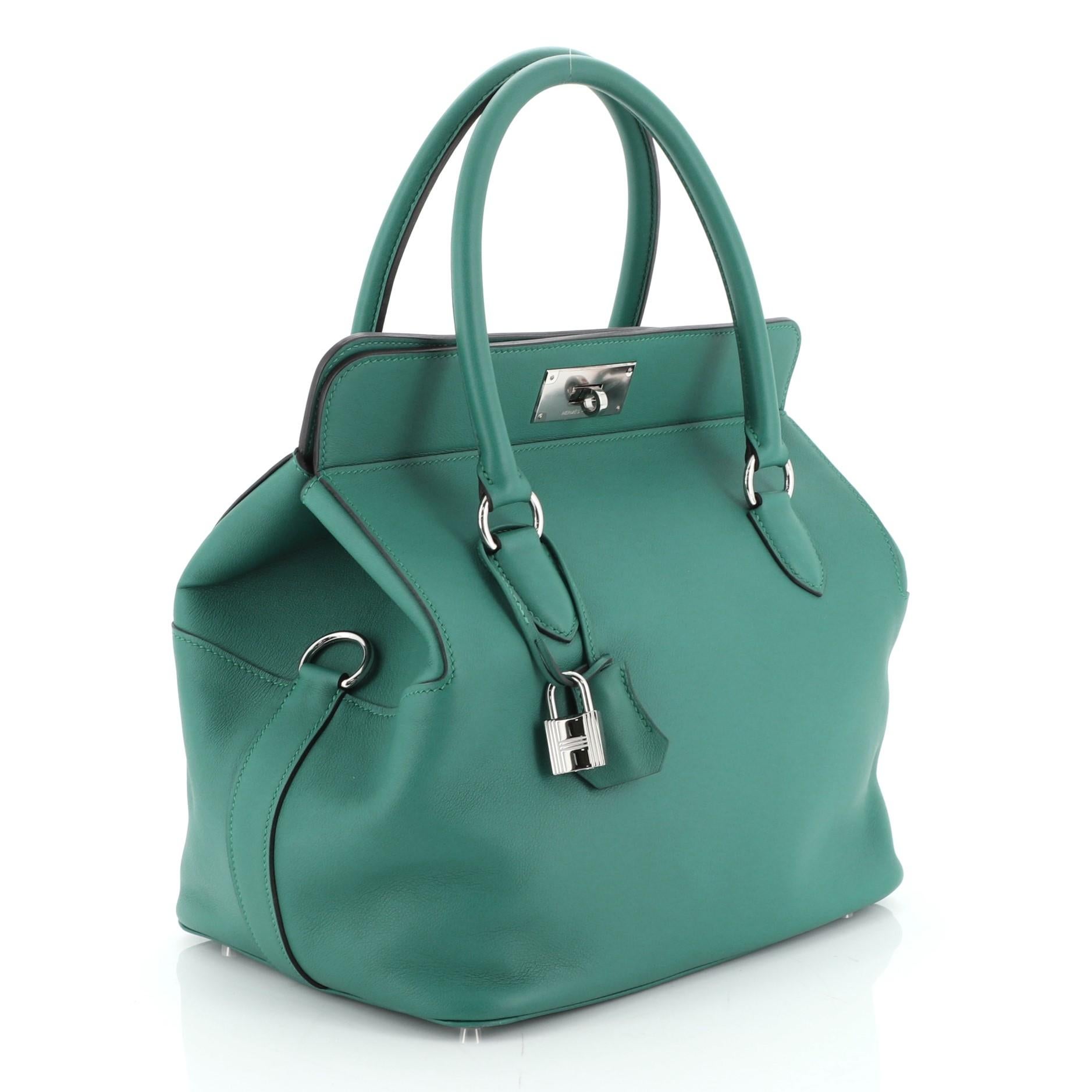 This Hermes Toolbox Handbag Swift 26, crafted from Malachite green Swift leather, features dual rolled handles, soft framed top, protective base studs, and palladium hardware. Its turn-lock closure opens to a Malachite green Swift leather interior