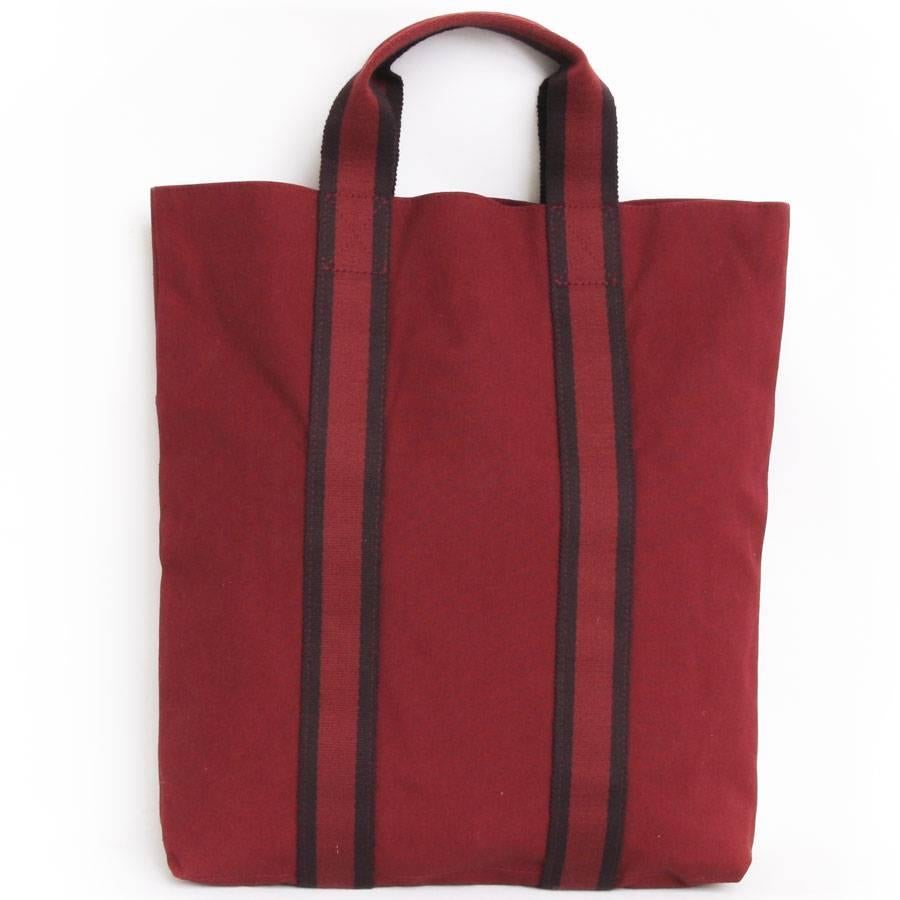 Hermès tote bag, red H canvas with red H and dark purple strips. New condition. 

At the front, 3 compartments. The interior is lined in the same material and in the same color.

The brand label is missing. Worn by hand and can hold folders or a