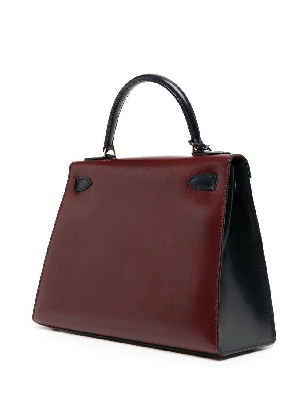 Crafted from high-shine leather, this Kelly 28 two-way bag has a contrasting combination of dark green, navy blue and burgundy hues, and refined gold-tone hardware. A highly sought-after style. From 1992, this bag is in excellent