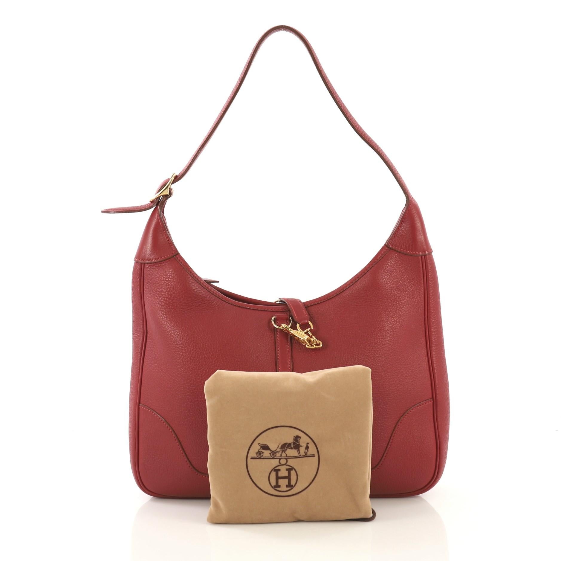 This Hermes Trim II Bag Clemence 31, crafted in Rouge Vif red Clemence leather, features looped shoulder strap and gold hardware. Its clasp closure opens to a Rouge Vif red raw leather interior with side zip and slip pockets. Date stamp reads: B