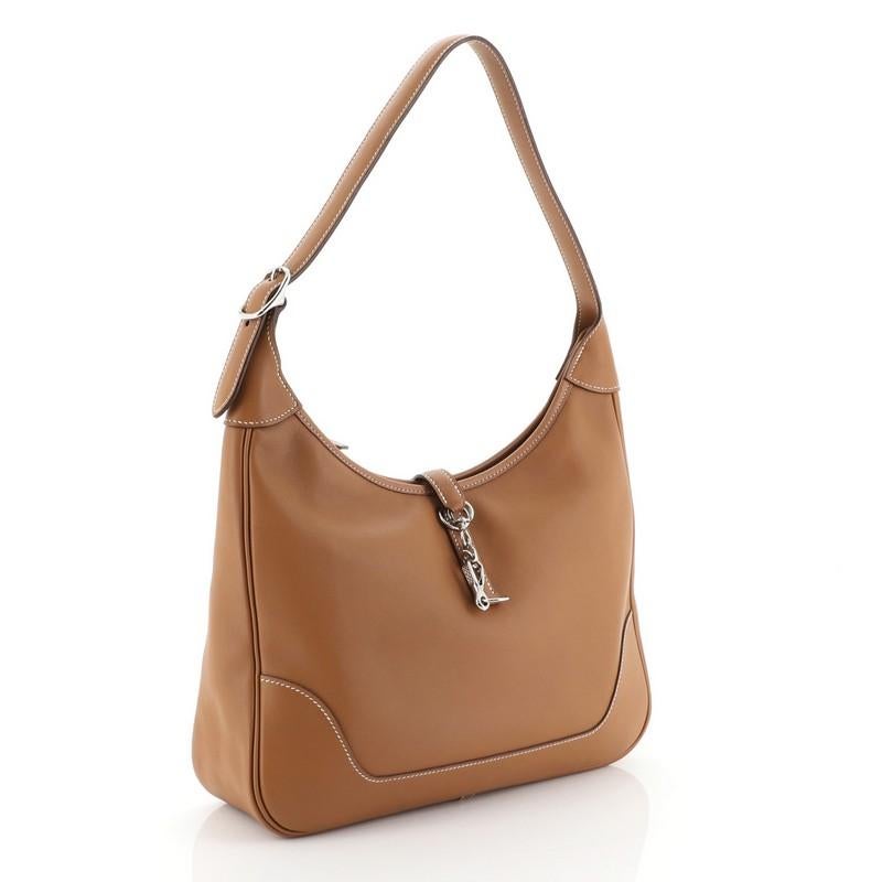 This Hermes Trim II Bag Swift 31, crafted in Gold brown Swift leather, features looped shoulder strap and palladium hardware. Its clasp closure opens to a Gold brown raw leather interior with side zip and slip pockets. Date stamp reads: J Square