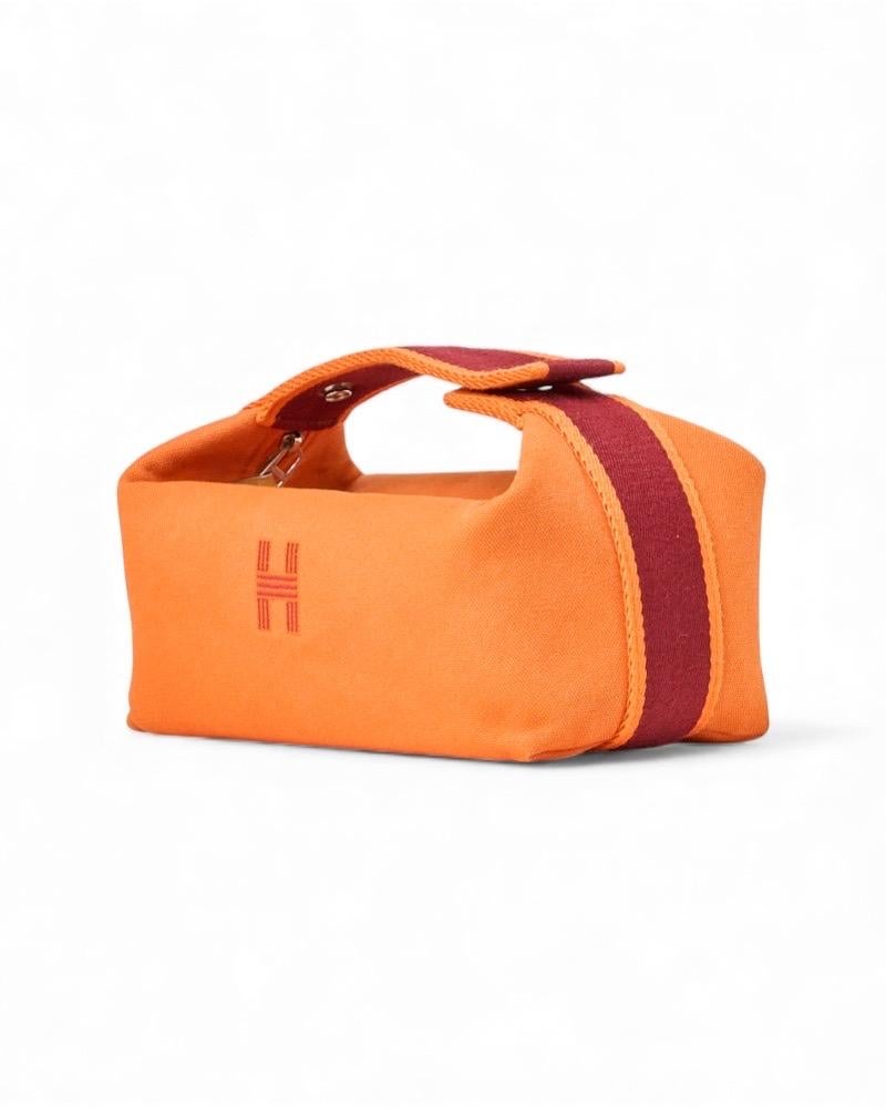 Trousse firmato Hermès, modello Bride-à-Brac, realizzato in tela arancione con hardware argento. Ausgestattet mit einem Reißverschluss, innen in beigefarbenem Leder und mit bequemen Taschen, ist die Tasche sehr leicht zu tragen. Munita di un manico