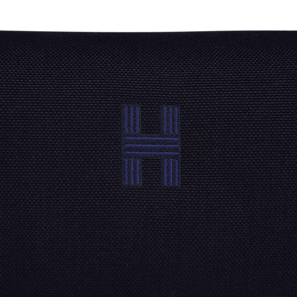 Mightychic offers an Hermes Trousse de Toilette case featured in Black H Plume canvas.
Blue embroidered H on the front.
Top strap, inspired by a Gianpaolo Pagni drawing, features an woven Bleu zig zag.
With two Clou de Selle snaps, the strap opens