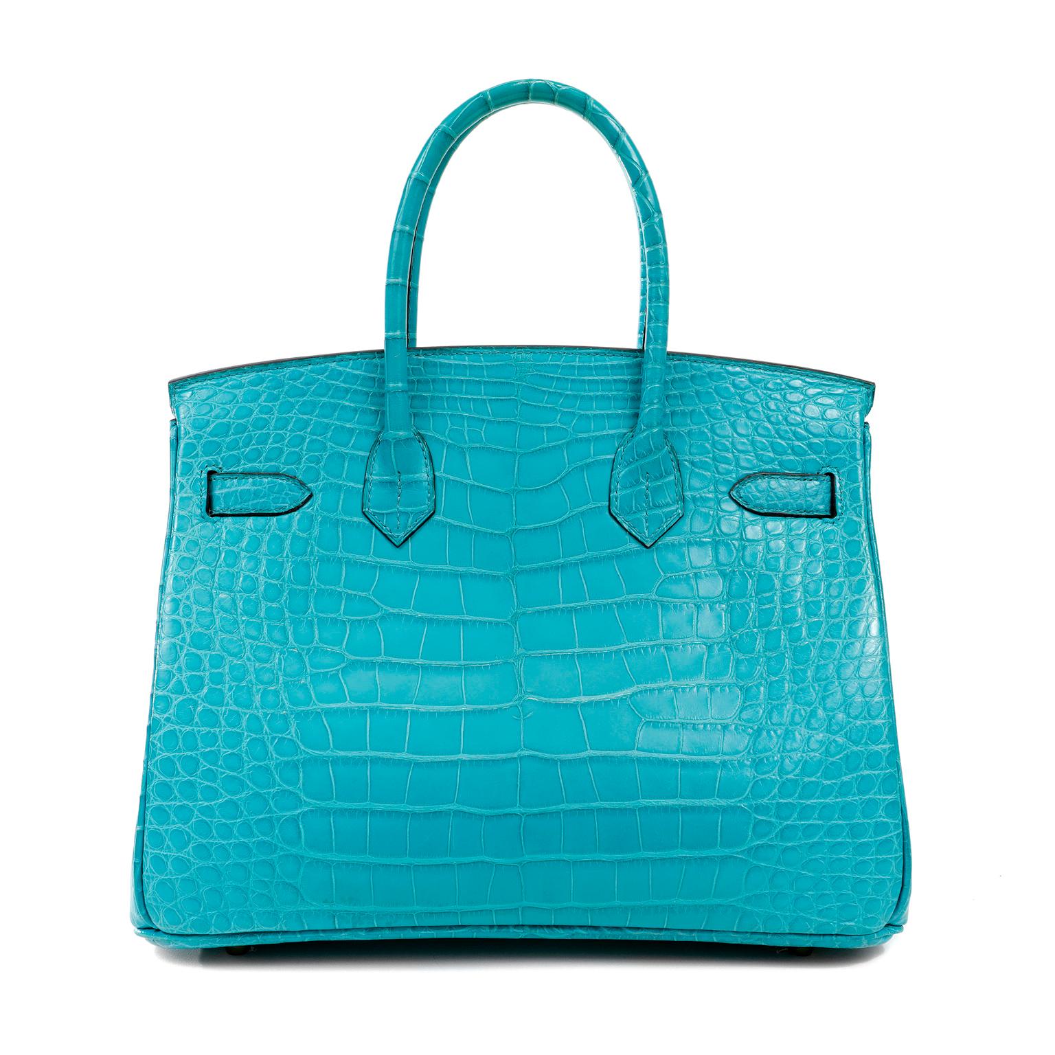 This authentic Hermès Blue Paon Crocodile 30 cm Birkin is in pristine unworn condition with the protective plastic intact on the hardware.   Hermès bags are considered the ultimate luxury item the world over.  Hand stitched by skilled craftsmen,