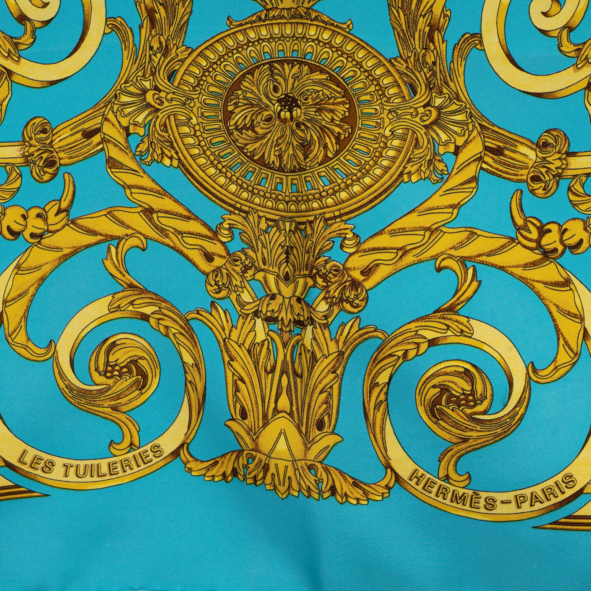 Questo foulard Les Tuileries 90 di Hermès, autentico al 100%, è realizzato in twill di seta turchese con bordi arrotolati a mano. Disegnato da Joachim Metz, presenta un'intricata stampa in oro antico ispirata alla grandezza dell'architettura