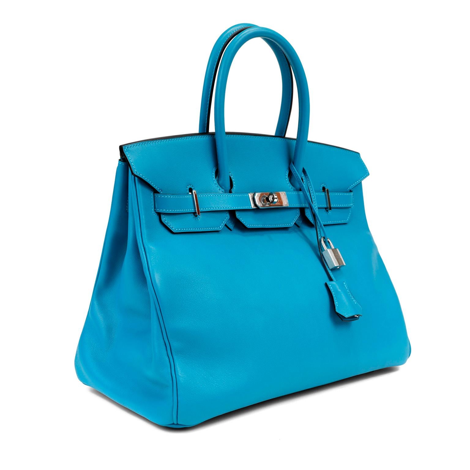 This authentic Hermès Turquoise Swift Leather 35 cm Birkin Bag is in pristine condition with plastic intact on the hardware.  Long waitlists are commonplace for the intensely coveted classic leather Birkin bag.  Each piece is hand sewn by skilled