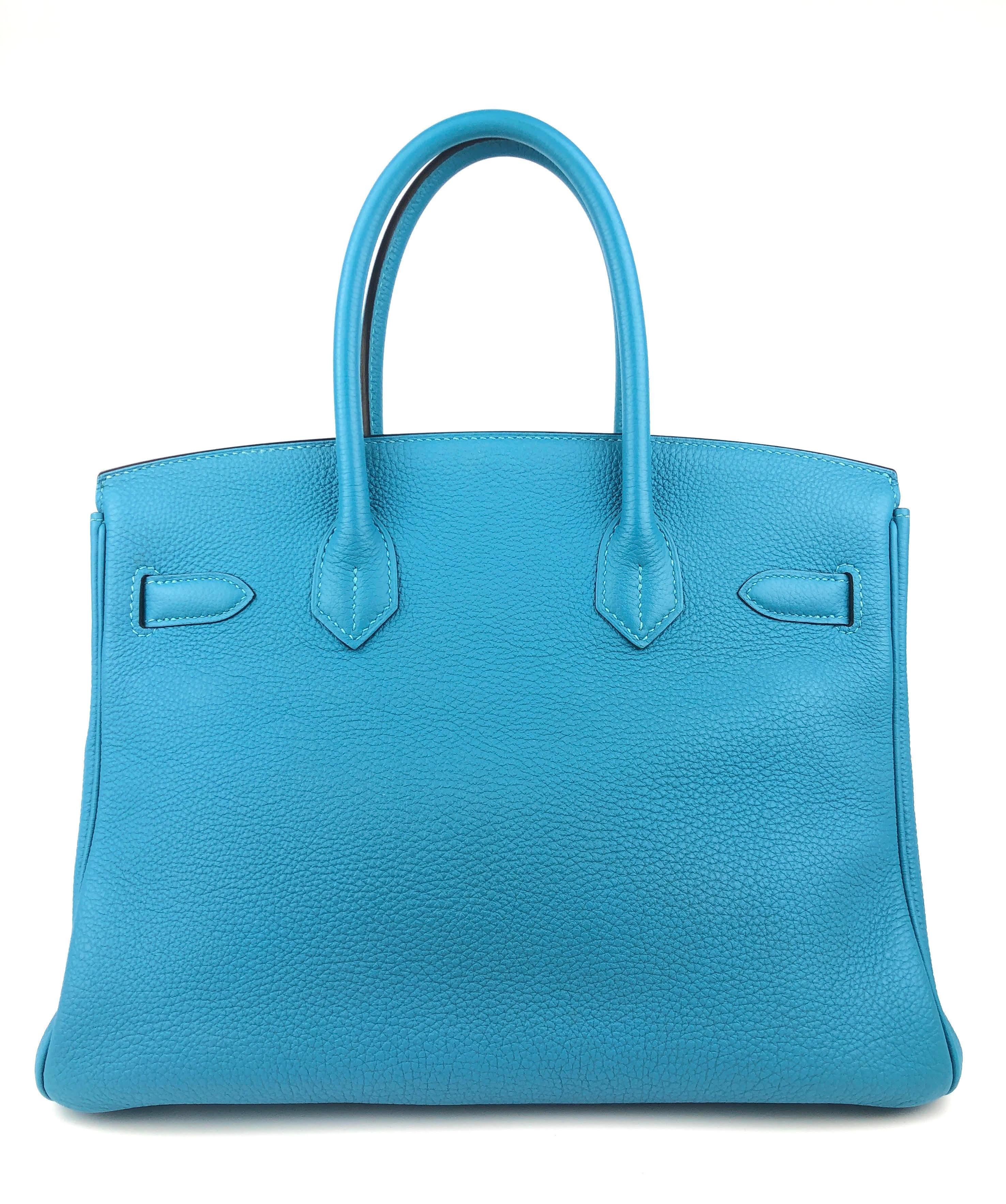 This authentic Hermès Turquoise Togo 30 cm Birkin is in pristine unworn condition with the protective plastic intact on the hardware.  Waitlists exceeding a year are commonplace for the intensely coveted classic leather Birkin bag.  Each piece is