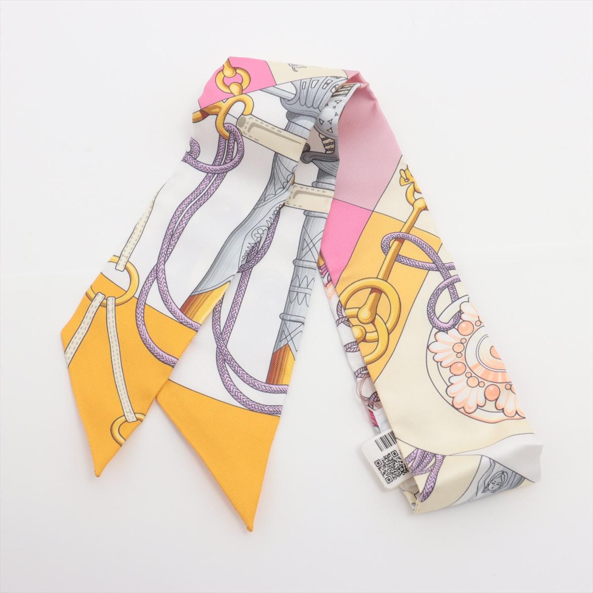 The Hermès Twilly Cliquetis Silk in Yellow is a vibrant and elegant accessory featuring an intricate equestrian-inspired chain and buckle motif. Crafted from luxurious silk, the twilly showcases Hermès' signature craftsmanship and artistic
