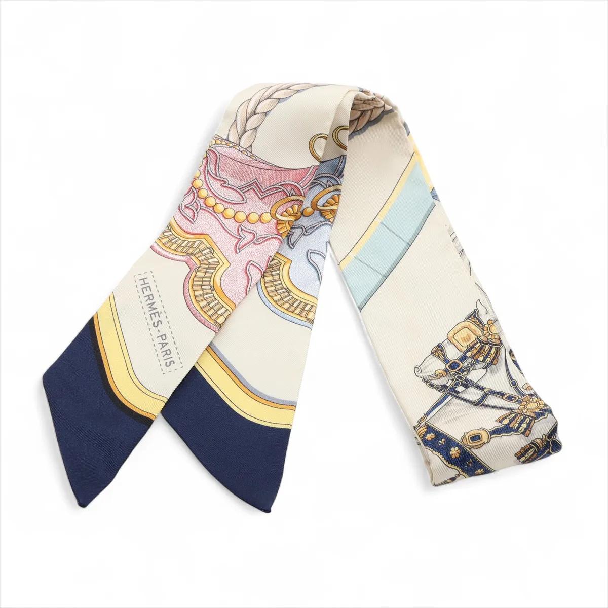 The Hermès Twilly Grand Apparat Horses Scarf in silk ivory is a delicate and elegant accessory that showcases the house’s artistry and heritage. Crafted from luxurious silk, it features the intricate Grand Apparat motif with beautifully detailed