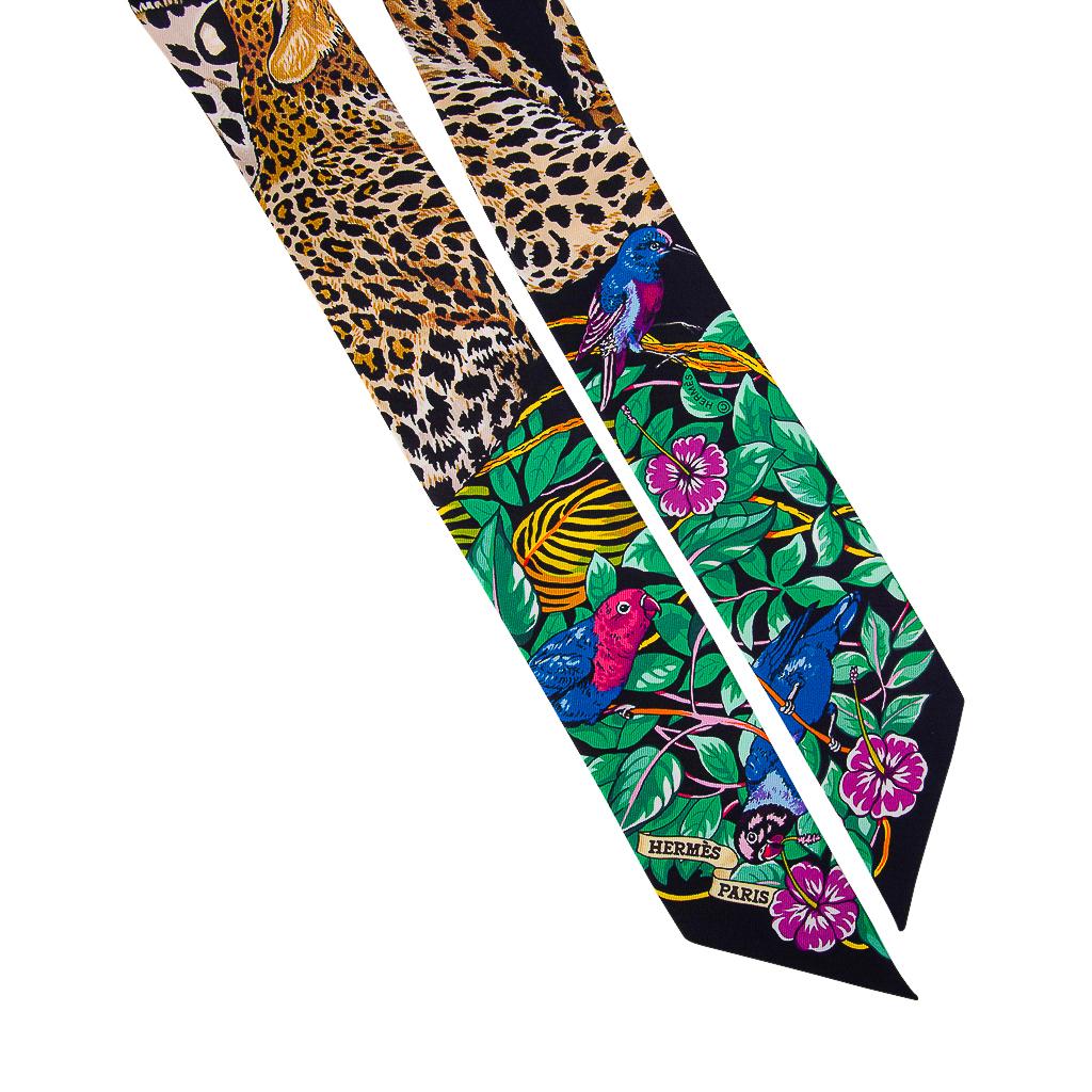 Hermes Twilly features limited edition Jungle Love Love featured in rich Noir / Vert and Rose Vif. 
Rose Vif Hearts sprinkled against the Black background.
This iconic Hermes accessory can be worn in a variety of ways to add a playful touch to your