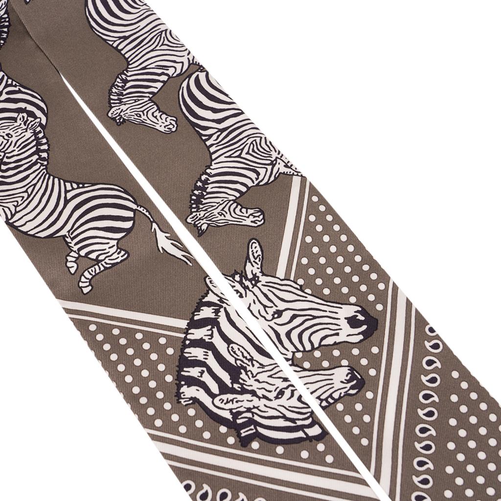 Mightychic offers a rare Hermes Twilly set of two (2) Les Zebres in Gris Taupe and Noir.
Black and White Zebras against the Gris Taupe background.
Designed by Robert Dallet.
This iconic Hermes accessory can be worn in a myriad ways to add a playful