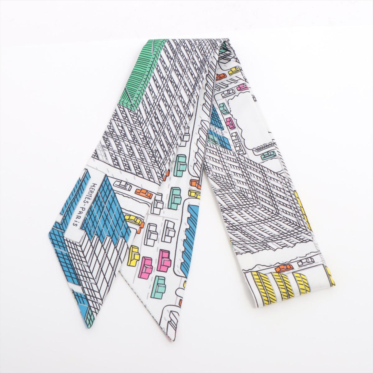 The Hermès Twilly Pantin City in White is a delicate silk accessory featuring a playful and artistic design inspired by the vibrant energy of Pantin, a creative hub near Paris. With intricate illustrations and a refined color palette set against a
