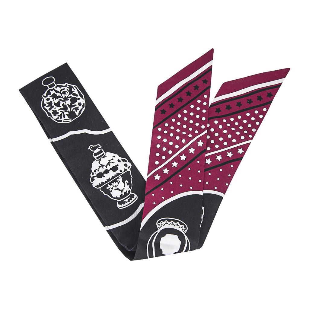 Guaranteed authentic Hermes Twilly silk scarf  Les Flacons Bandana featured in rare to find in Black with Bordeaux.
This iconic Hermes accessory can be worn in a myriad ways to add a playful touch to your wardrobe.
And of course express your own