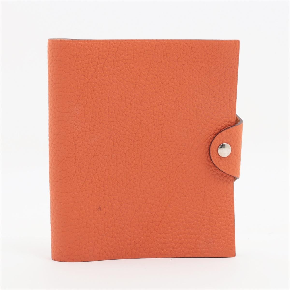 Das Hermès Ulysse PM Togo Notebook Cover in Orange ist ein luxuriöses Accessoire, das Funktionalität mit tadelloser Handwerkskunst verbindet. Das Notebook-Cover aus robustem Togo-Leder strahlt Raffinesse und Eleganz aus. Der leuchtende Orangeton