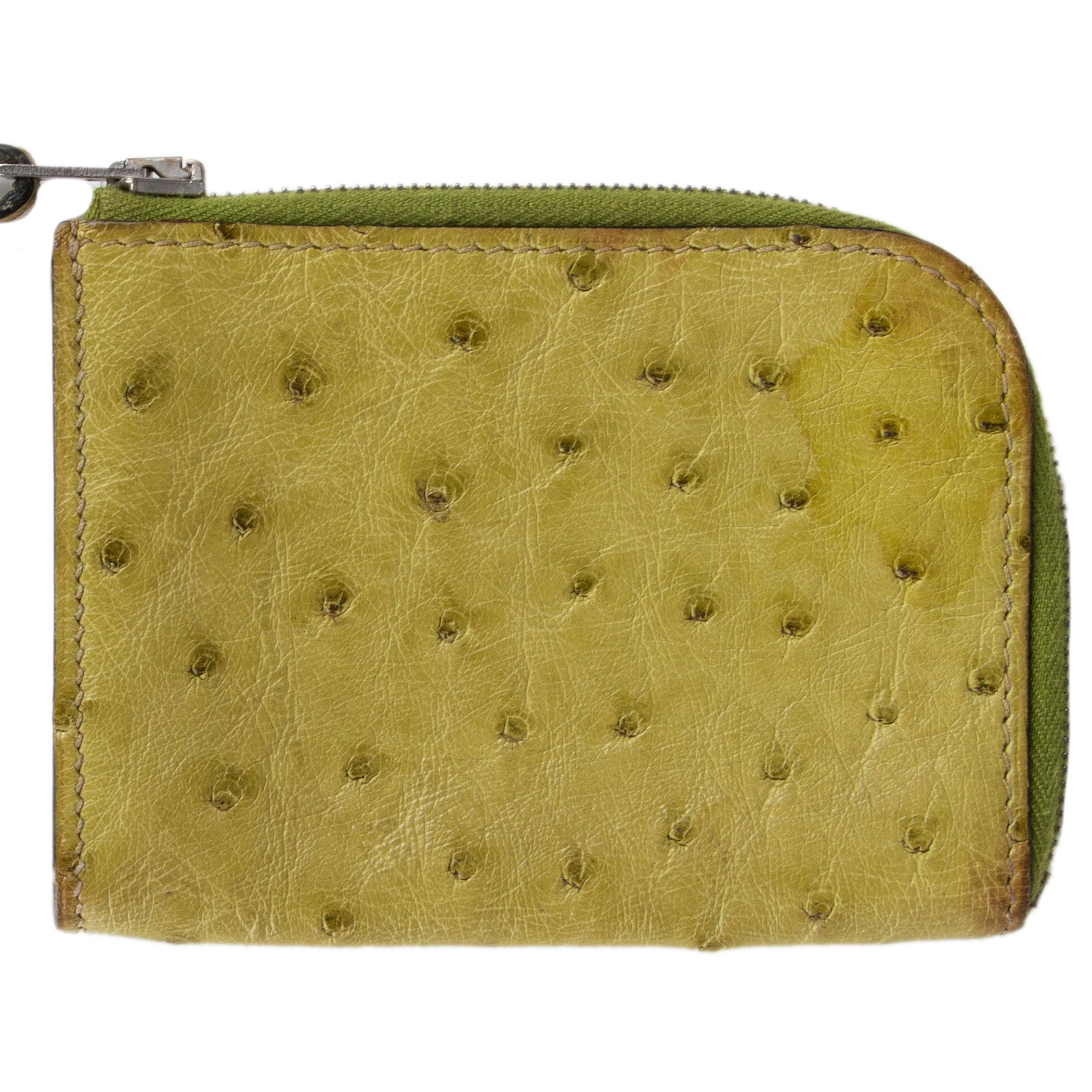 Hermes zip wallet with strap in Vert Anis (chartreuse) ostrich leather. Closes with a zipper. Lined in Chevre (goat skin). Has been carried and shows some overall darkening. Overall impression is very good.

Width 10cm (3.9in)
Height 7.5cm