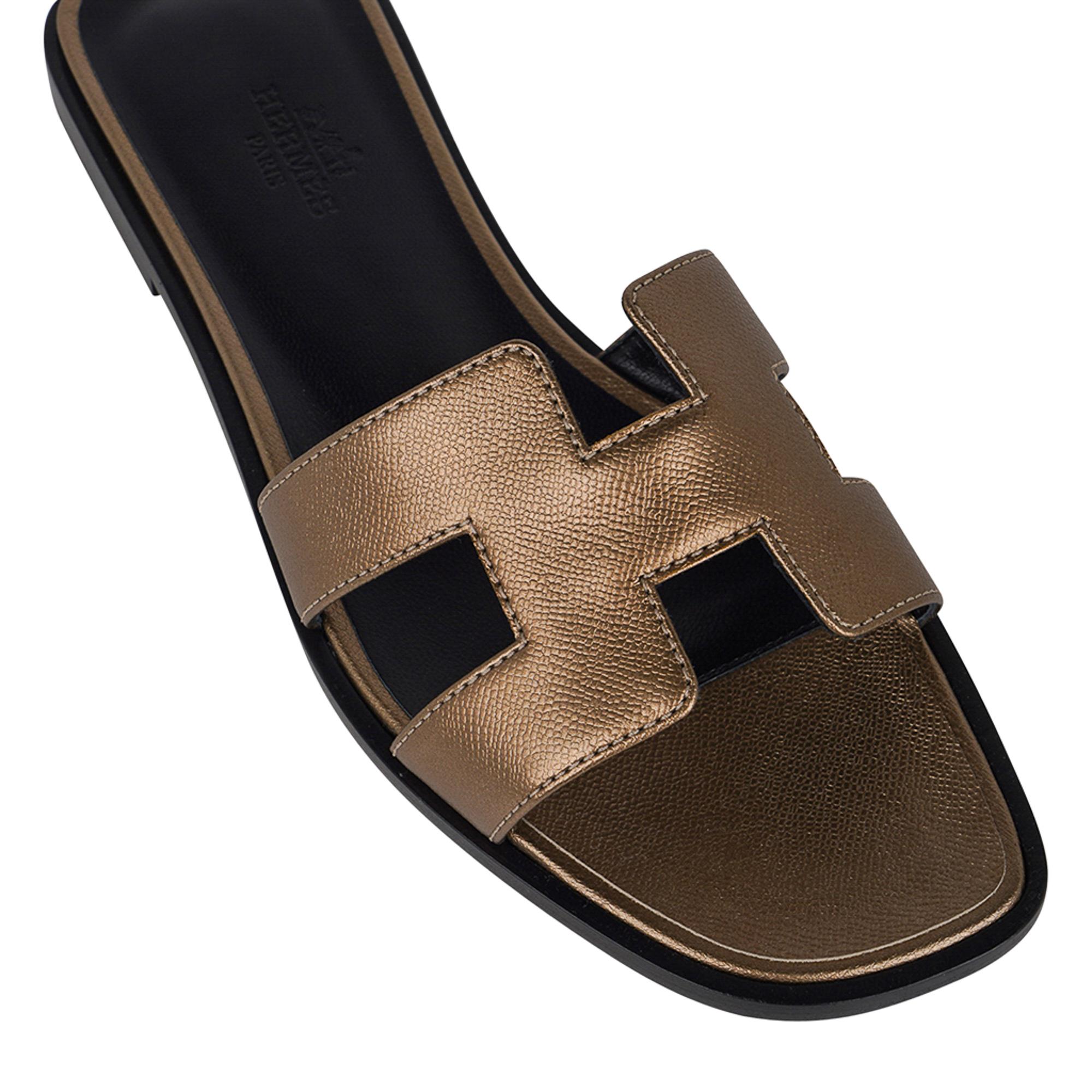 Mightychic offers a limited edition pair of Hermes Oran sandals featured in Metallic Vert Bronze.
Divine perfect neutral pairs with anything in your wardrobe!
This stunning limited edition Hermes Oran flat slide sandal is featured in Epsom