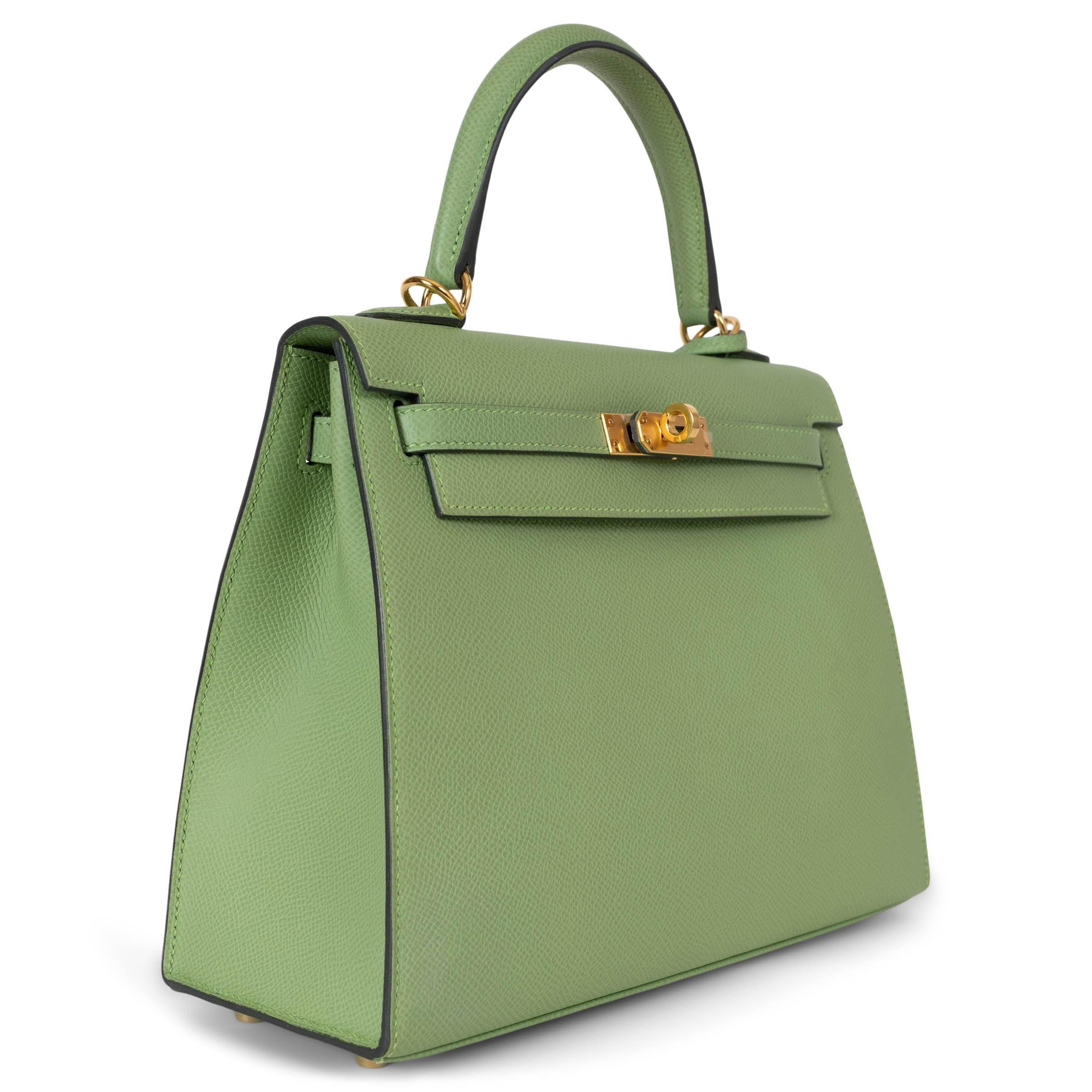 This 100% authentic Hermès Kelly 25 Sellier bag in Vert Criquet (pastel green) Veau Epsom leather is a stunning display of the brand's signature elegance. The structured silhouette is adorned with gold-plated hardware, including the iconic turn-lock