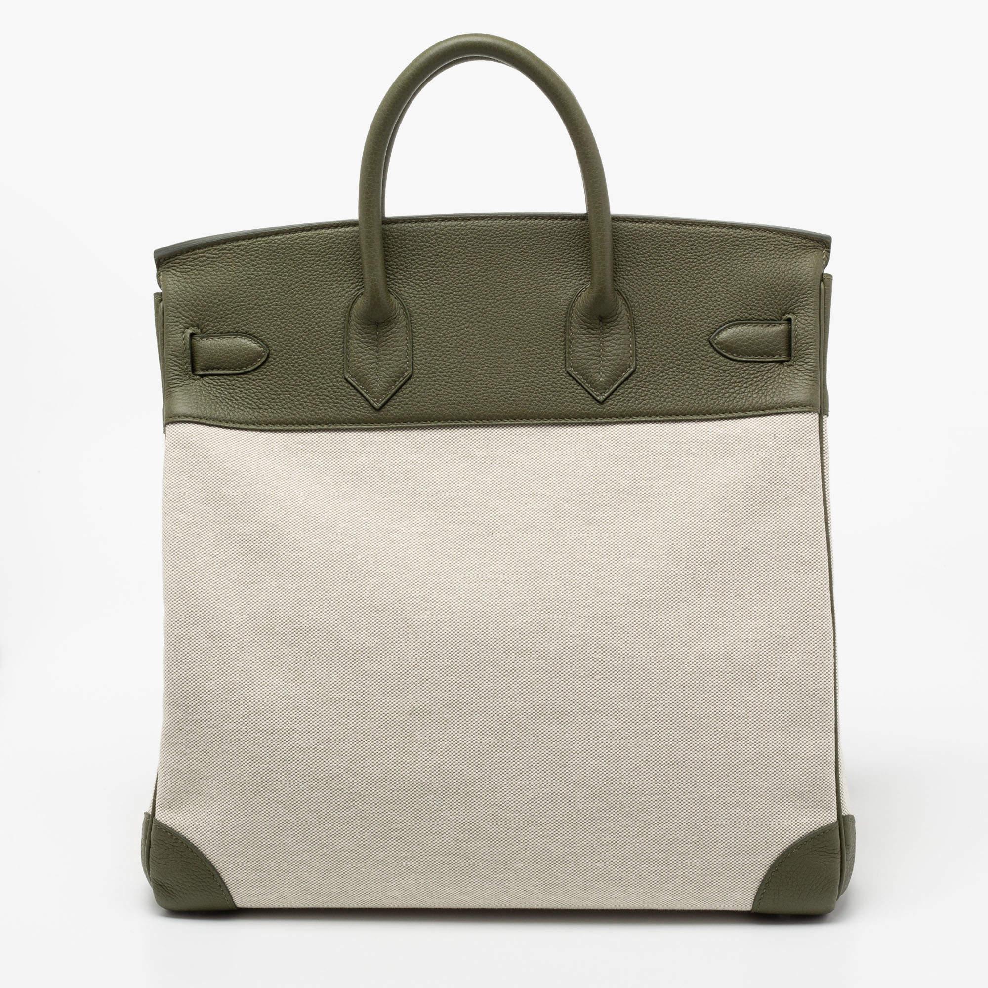 Timeless design coupled with rich craftsmanship, this Birkin HAC 40 bag is crafted from beige canvas and Vert Veronese leather. Its foldover top is secured by a palladium-finished lock, and the base is secured by studs. The interior of the bag has