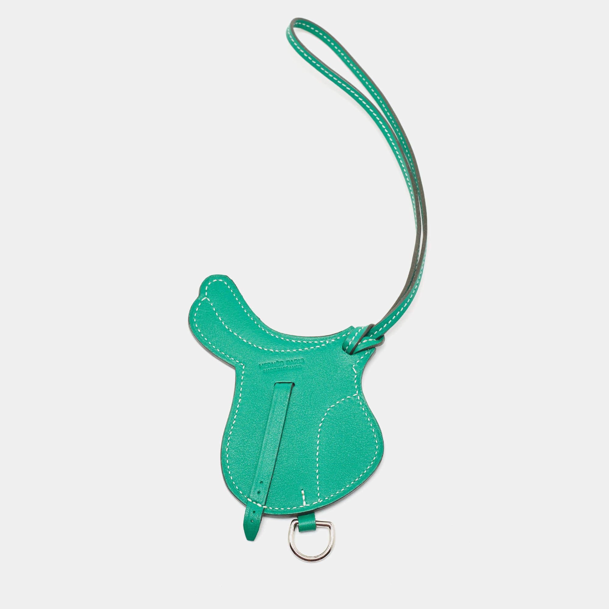 The Hermès Paddock Selle bag charm is an exquisite accessory crafted from luxurious Swift Leather. Its design features a captivating green shade. This charming piece perfectly complements any Hermès bag, adding a touch of elegance and