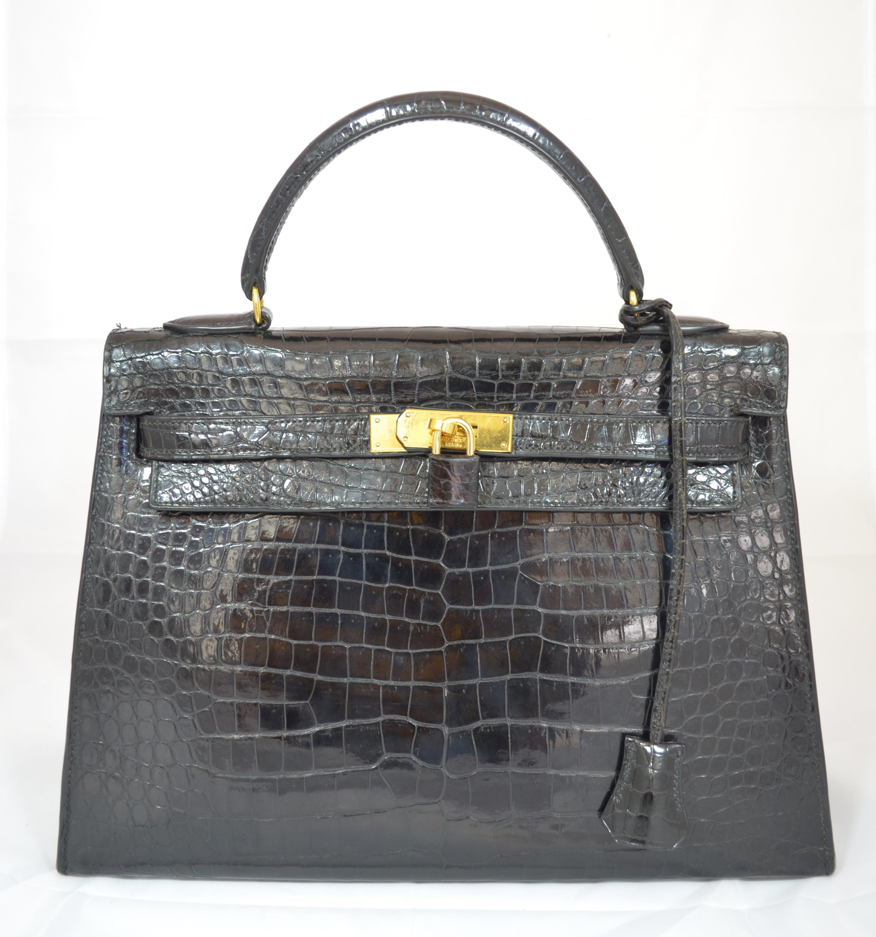 Hermès vintage Kelly bag featured in black crocodile with gold hardware, size 32cm, strap included, croc-covered padlock with cloche, fully lined leather interior with three slip pockets. Four protective metal feet at the base of the bag. Made in