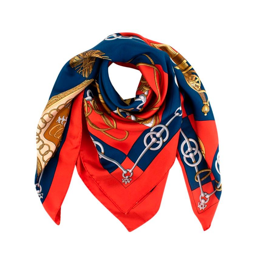 Hermes Vintage Cliquetis Red Blue & Gold Silk Twill Scarf

- Hermes Cliquetis print by Julia Abadie
- Features horse-bit trim borders and a military motif of swords, braided rope, and tassels
- Red and blue background with the design and signature