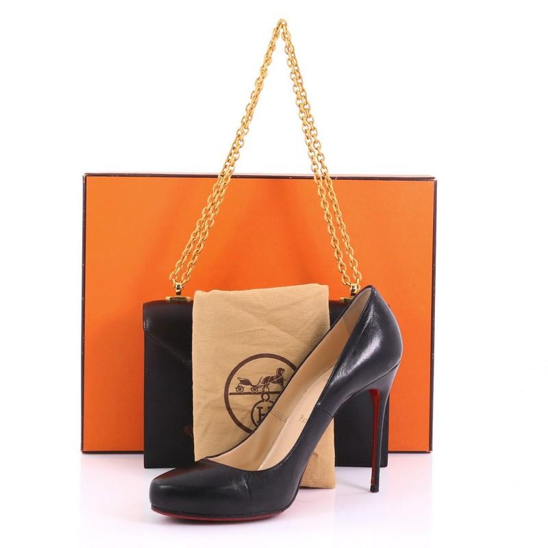 This Hermes Vintage Alcazar Chain Bag Box Calf Small, crafted in black box calf leather, features chain-link shoulder strap and gold-tone hardware. Its flip-lock closure opens to a black leather interior with zip and slip pockets. Date stamp reads: