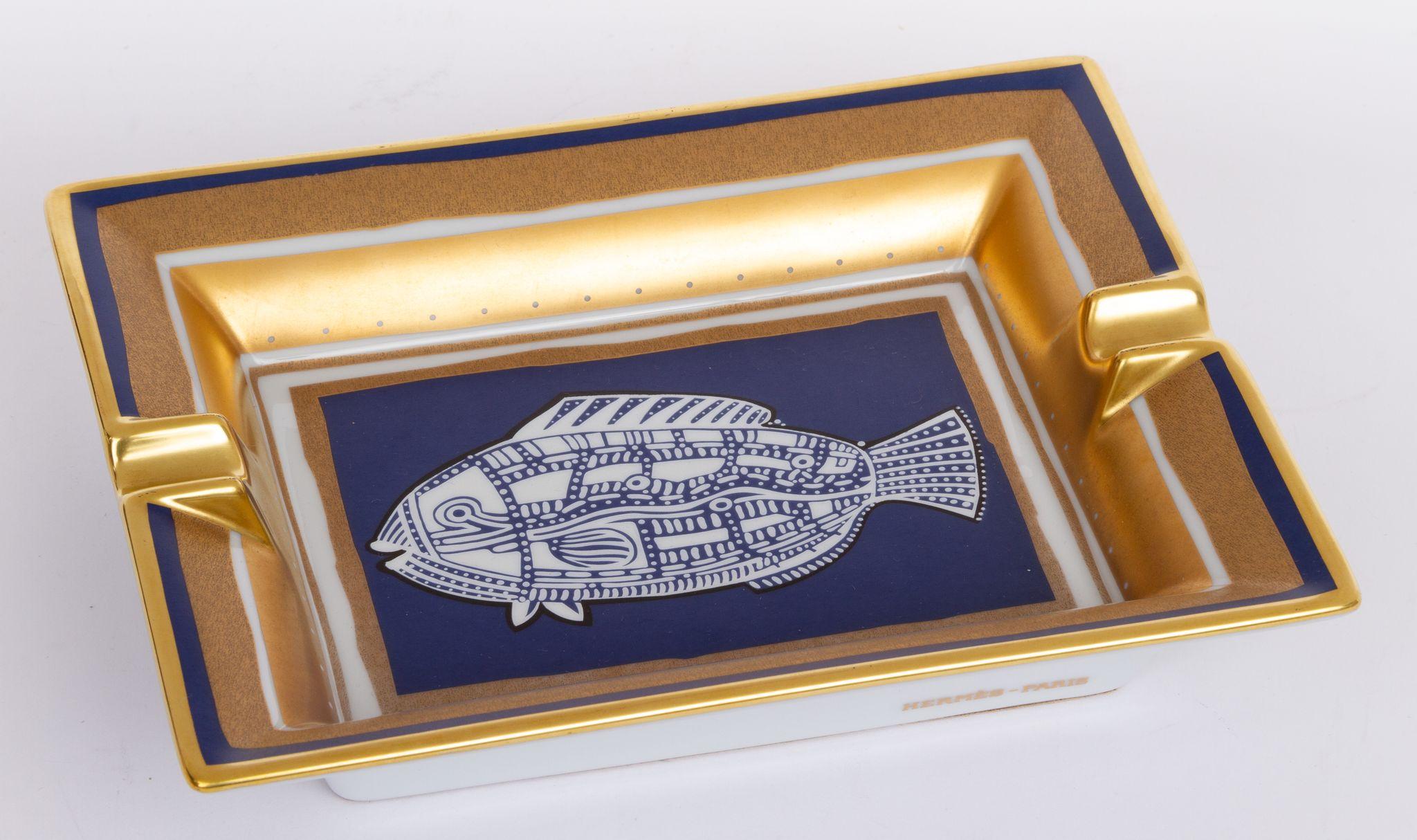Hermès vintage ashtray in blue and gold. In the center of the piece is a print of an abstract fish. The ashtray is in excellent condition.