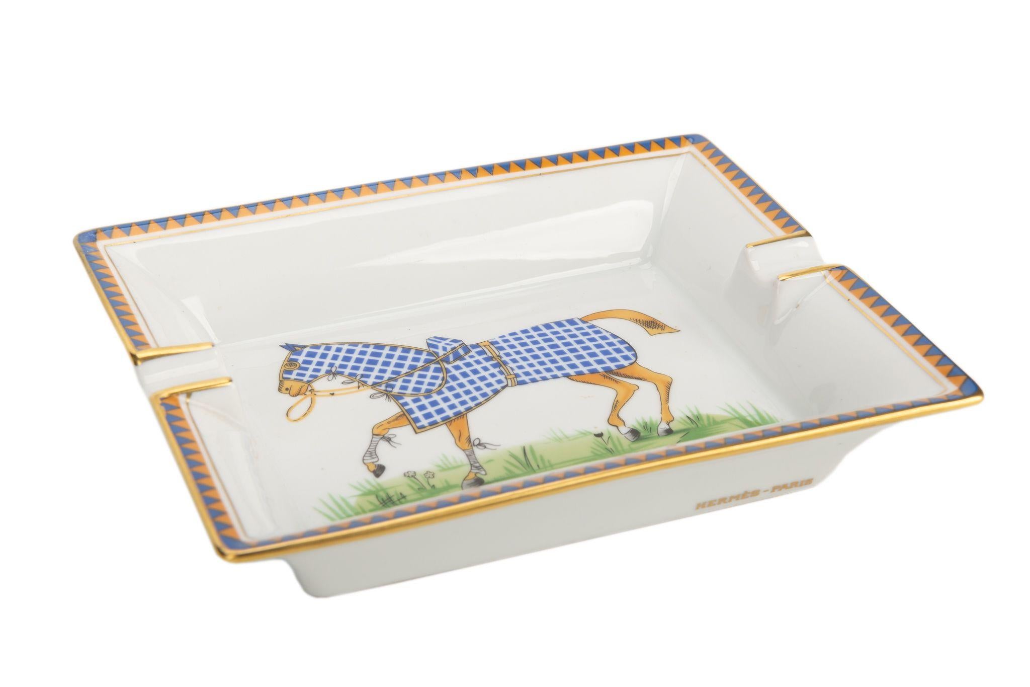 Hermès vintage ashtray in white porcelain with a horse in the center. The horse is decorated with a blue and white checkered blanket. Suede stamped bottom. The piece is in excellent condition.