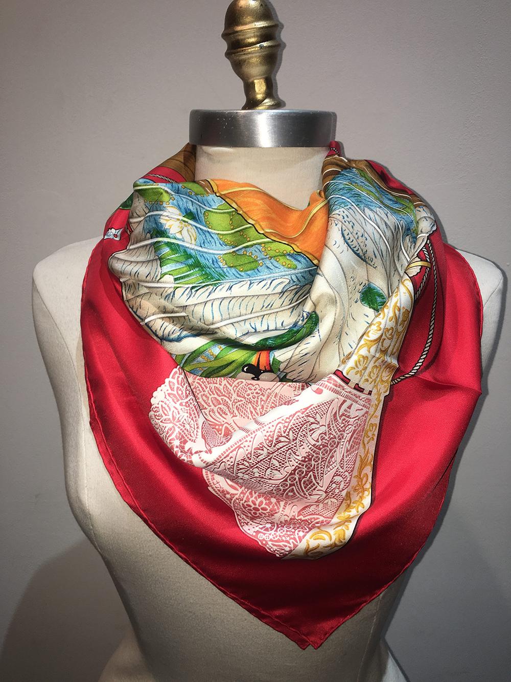 GORGEOUS Hermes Vintage Brise de charme silk scarf in excellent condition. Original silk screen design c1991 by Julia Abadie features an assortment of antique fans in lace, peacock, and horse prints over a bright red background. 100% silk, hand